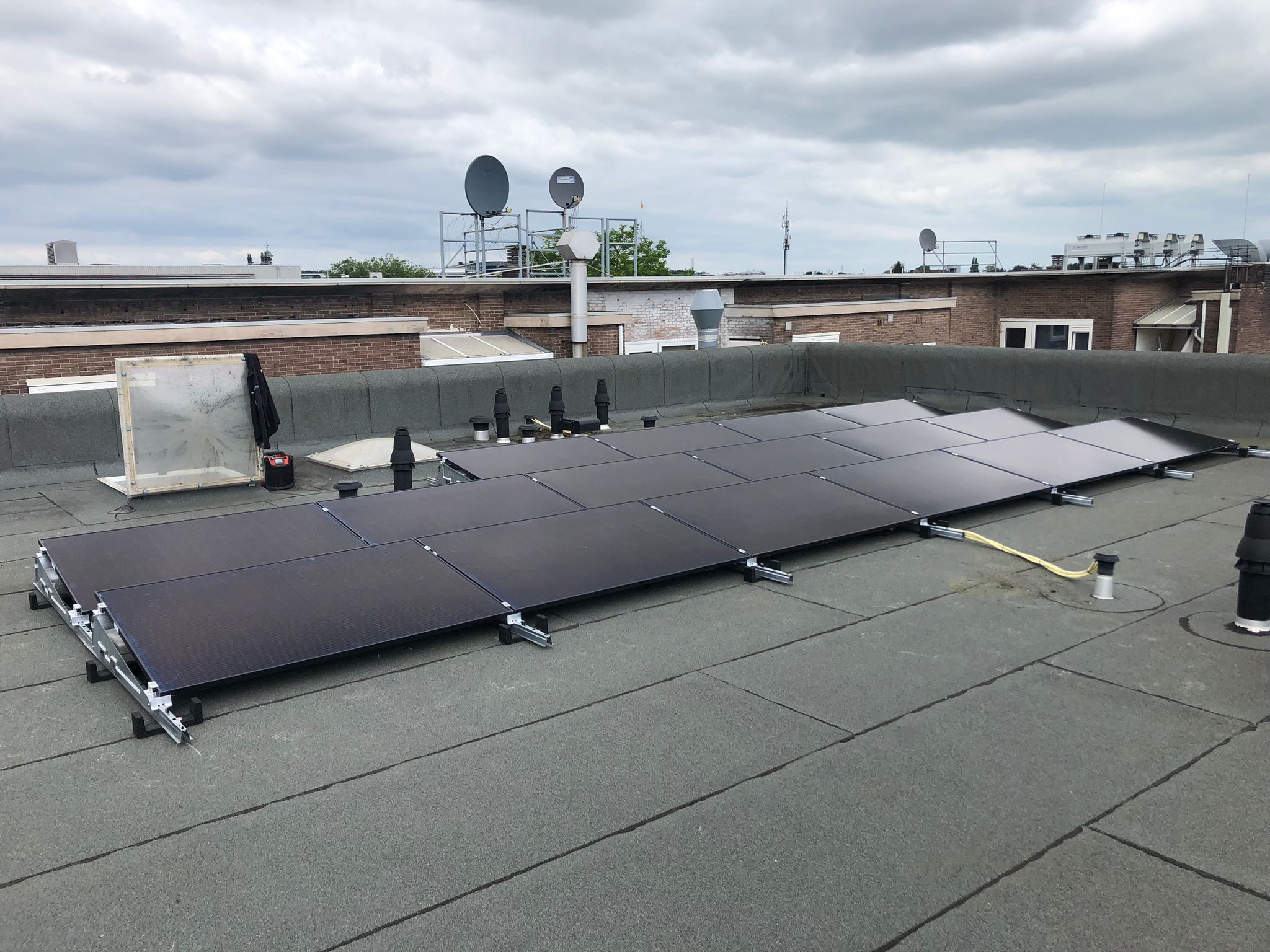 Deze afbeelding toont een installatie van zonnepanelen op een plat dak, met meerdere panelen goed zichtbaar en verbonden met de ondergrond.