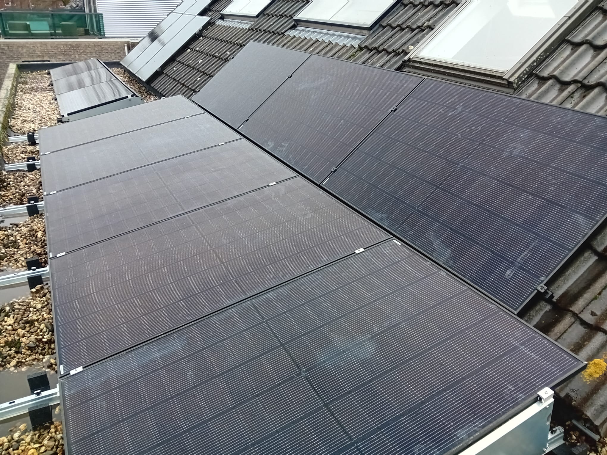 De foto toont een nette installatie van zonnepanelen op een schuine dakconstructie, optimaal gepositioneerd voor zonlicht.