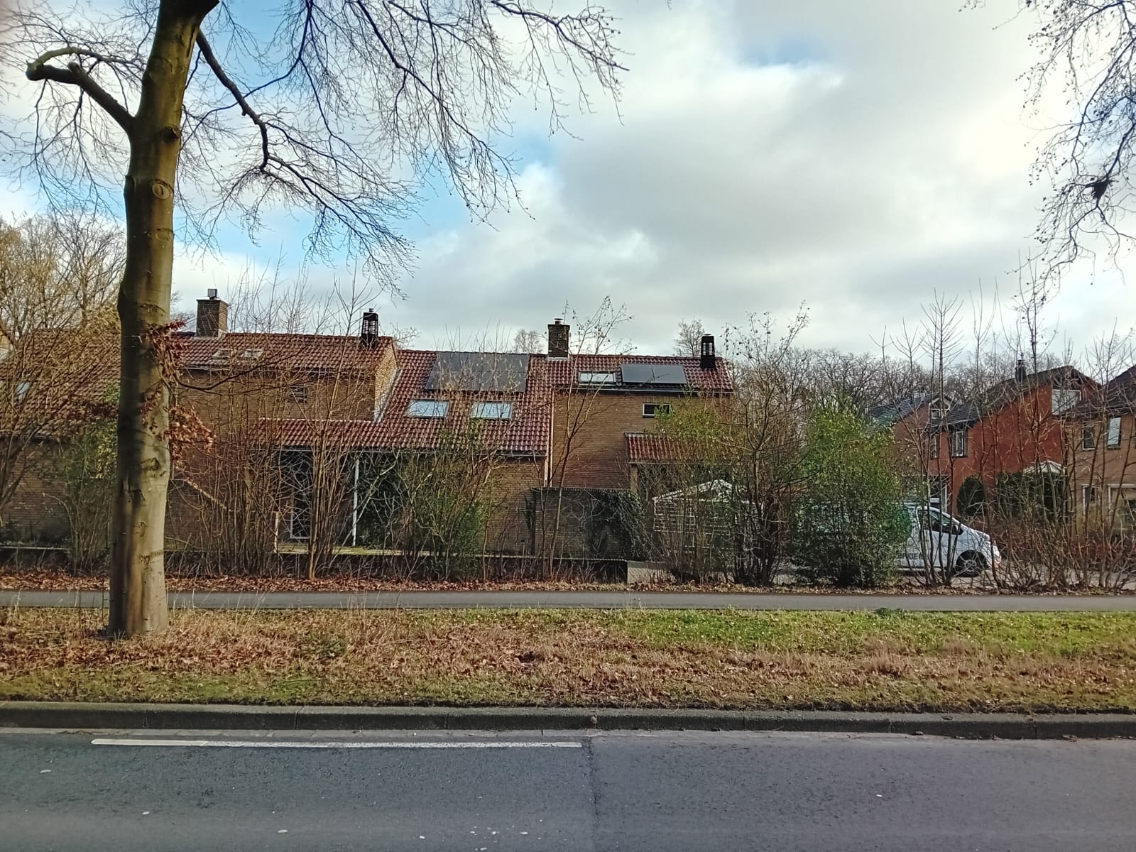 De afbeelding toont een woning met zonnepanelen geïnstalleerd op het dak, omringd door vegetatie.
