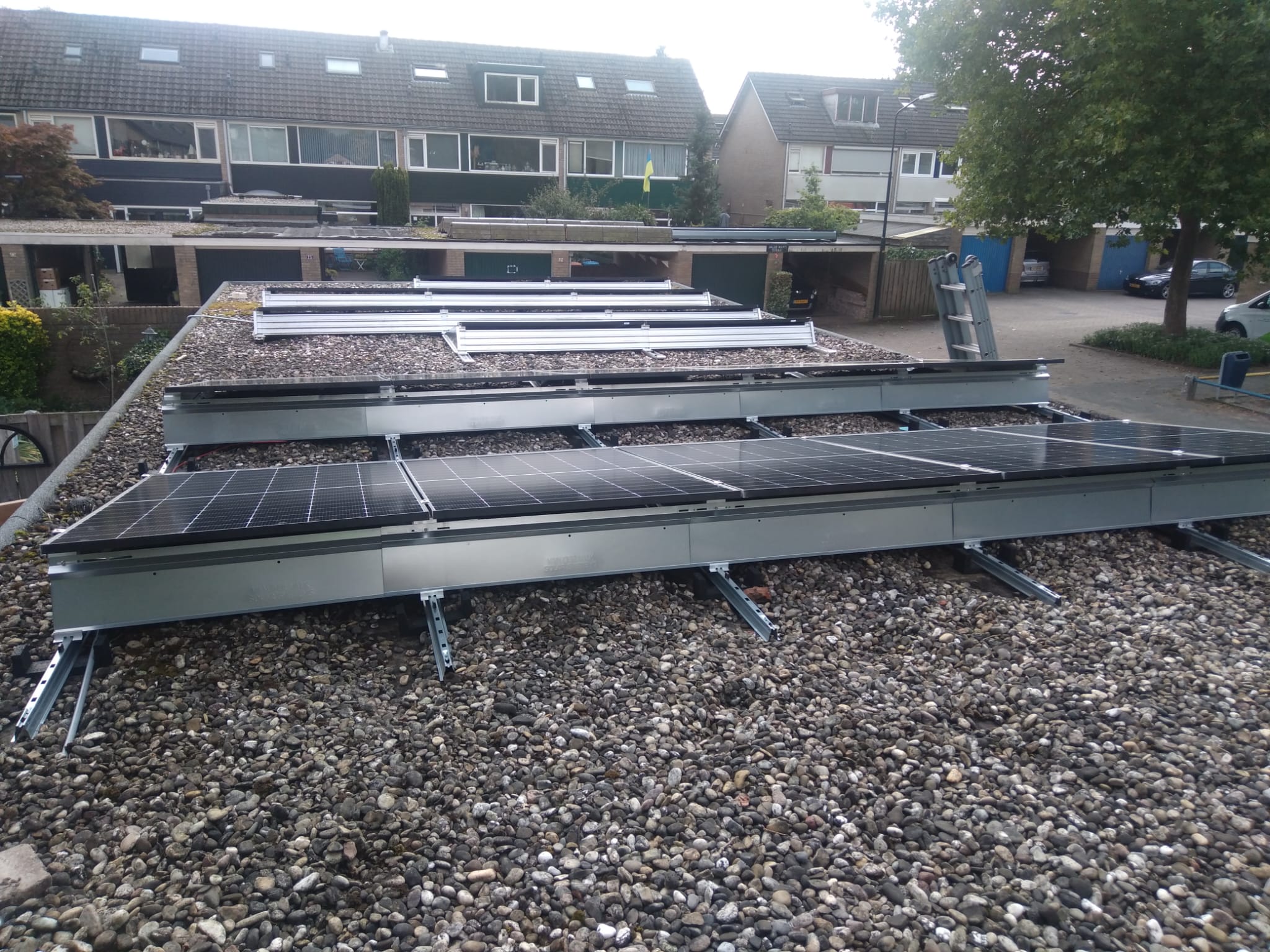 De installatie toont zonnepanelen die op een dak zijn gemonteerd met metalen steunen en grindbedekking.