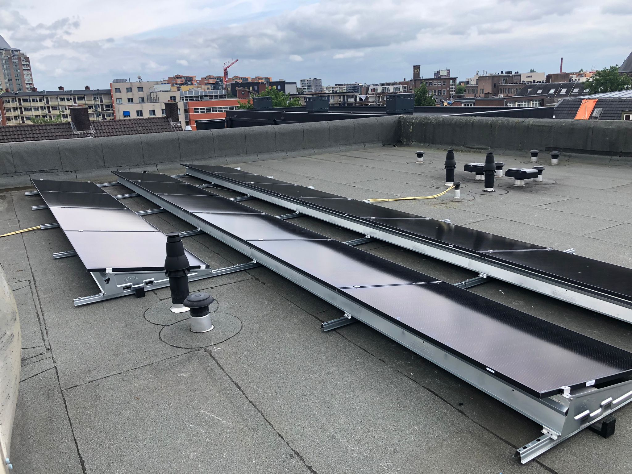 Deze afbeelding toont een installatie van zonnepanelen op een plat dak, gericht op het opwekken van zonne-energie.