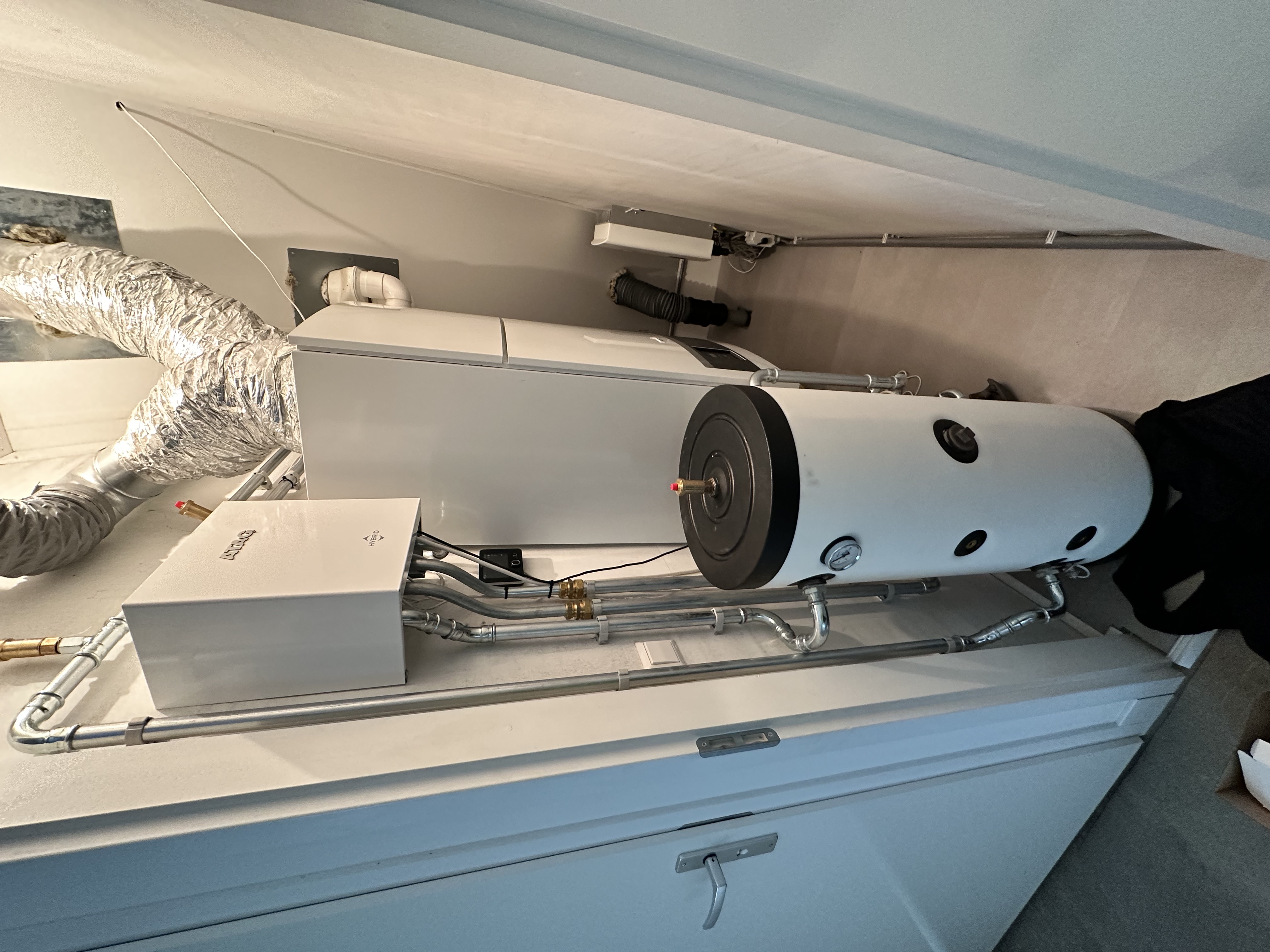 De foto toont een warmtepompinstallatie met een gecombineerde eenheid en opslagtank in een technische ruimte.