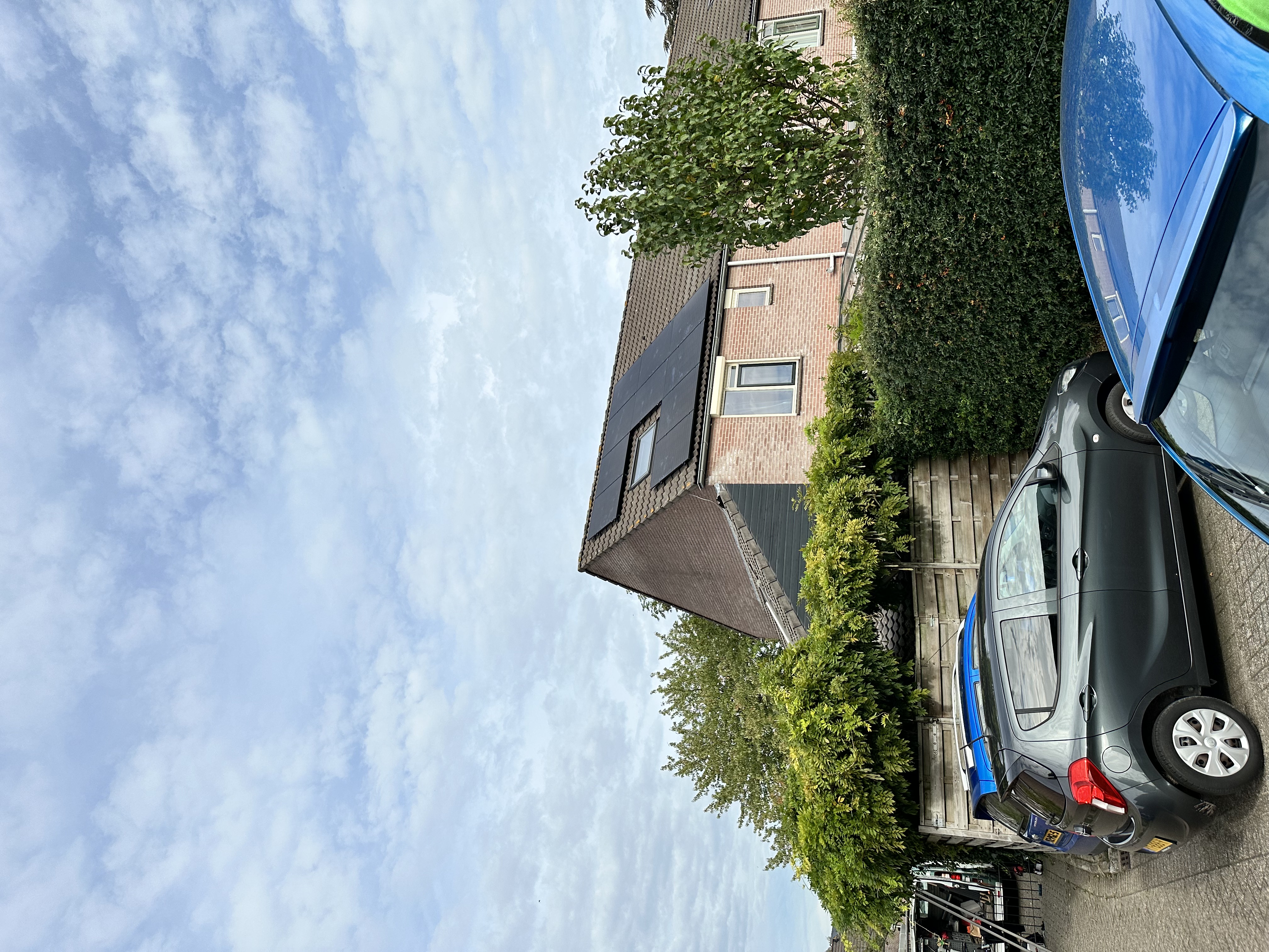 De afbeelding toont een woning met zonnepanelen op het dak, zichtbaar van een afstand. De installatie is geïntegreerd in de omgeving.