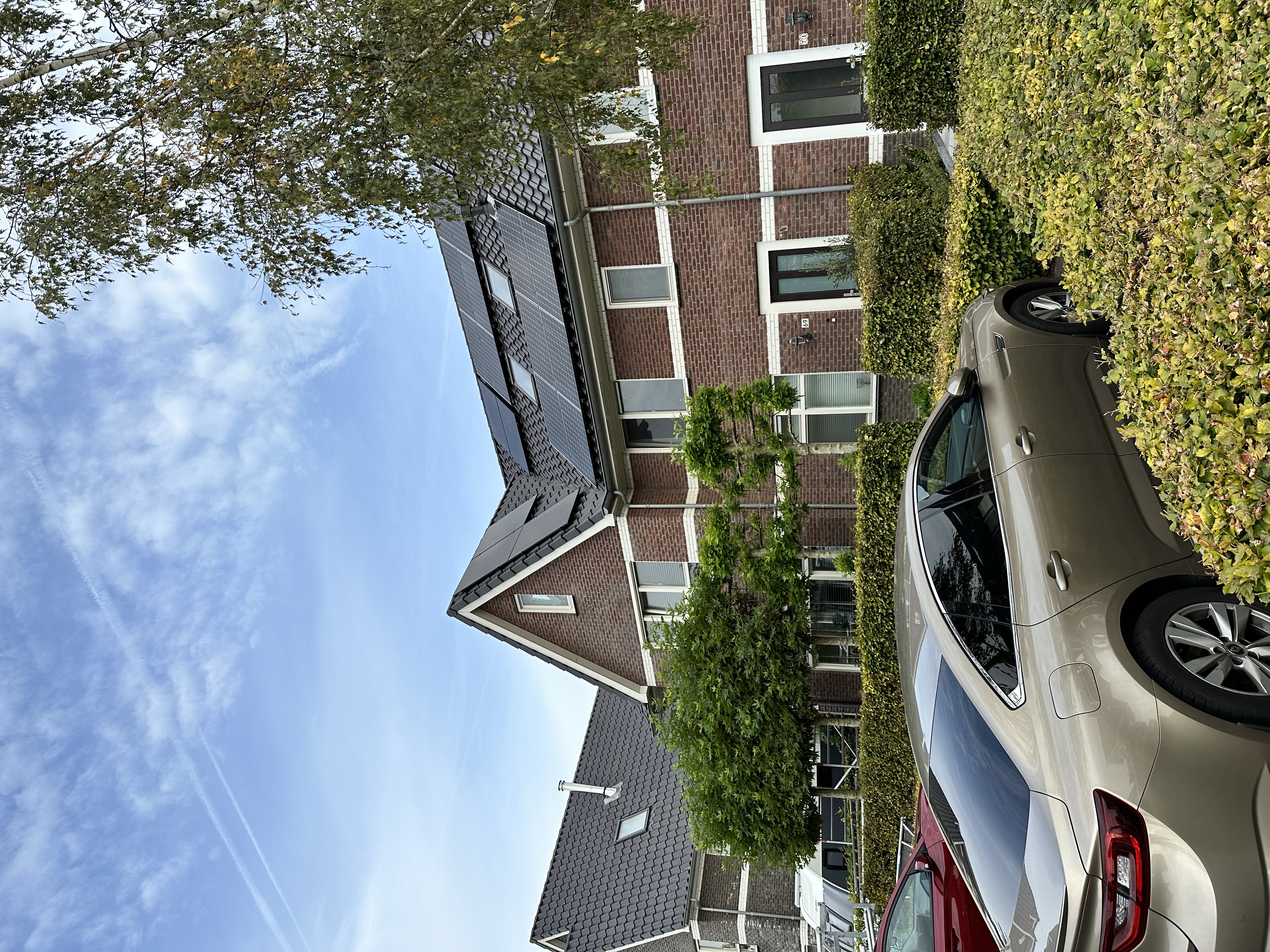 De afbeelding toont zonnepanelen geïnstalleerd op het dak van een woning, met een heldere blauwe lucht op de achtergrond.
