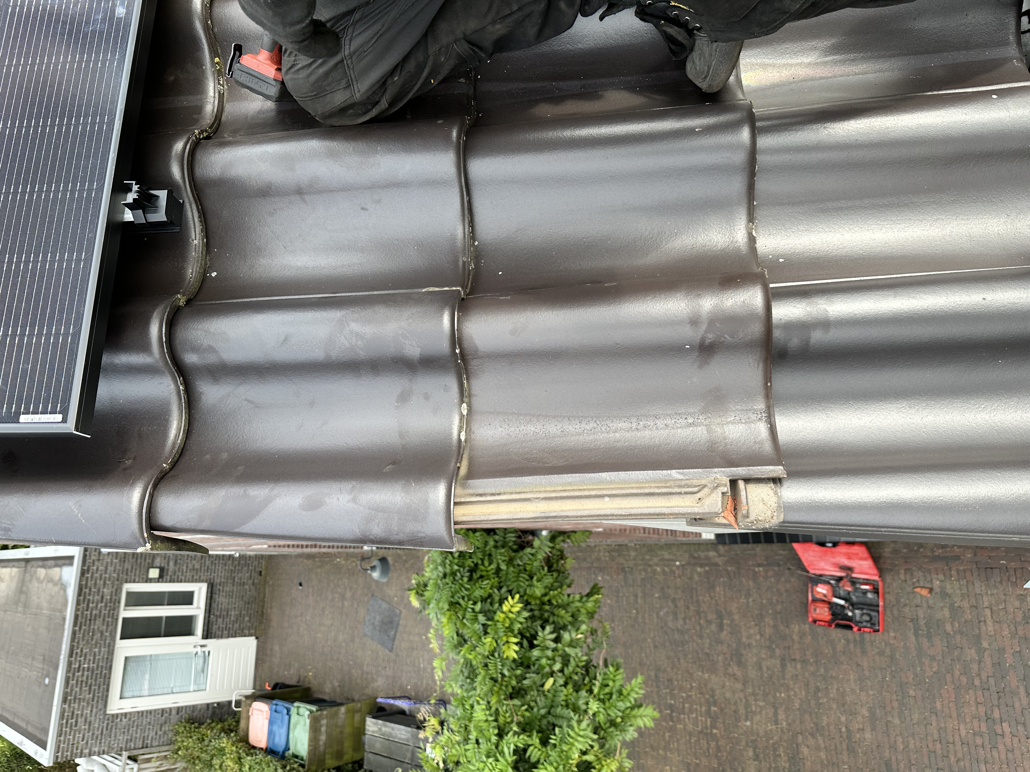 De afbeelding toont een zonnepaneleninstallatie op een dak, met een installateur die bezig is met de montage.