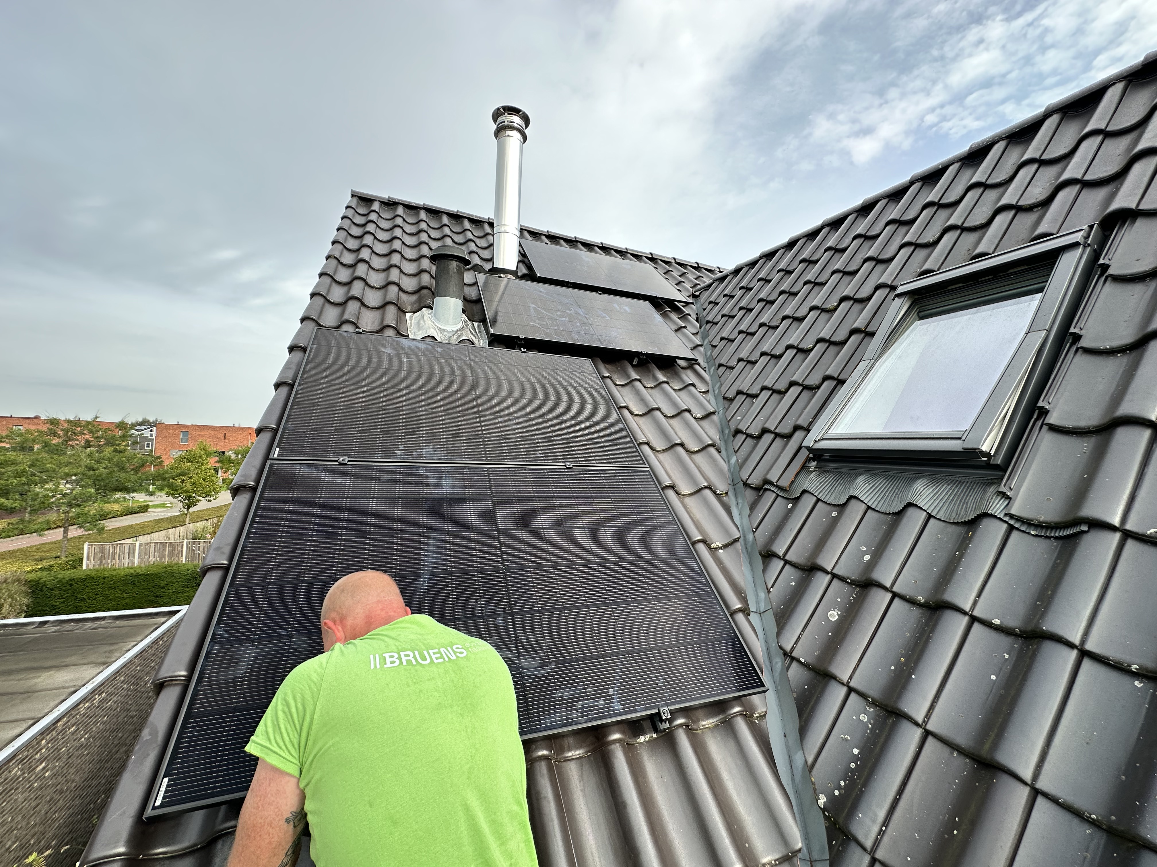 Een installateur plaatst zonnepanelen op een hellend dak, gericht op het benutten van zonne-energie.
