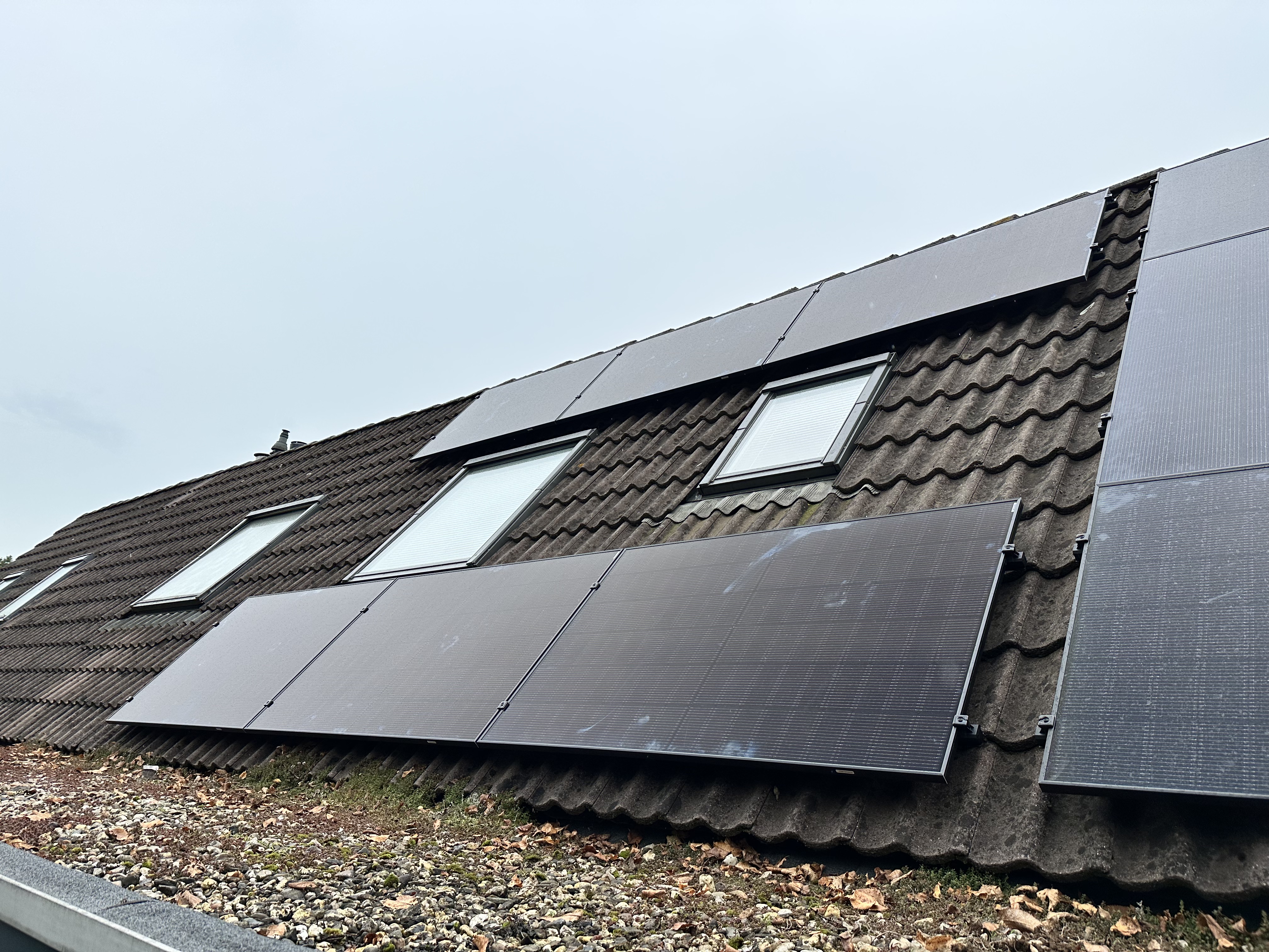 Een installatie van zonnepanelen op een hellend dak, gericht op duurzame energieoplossingen voor woningen.