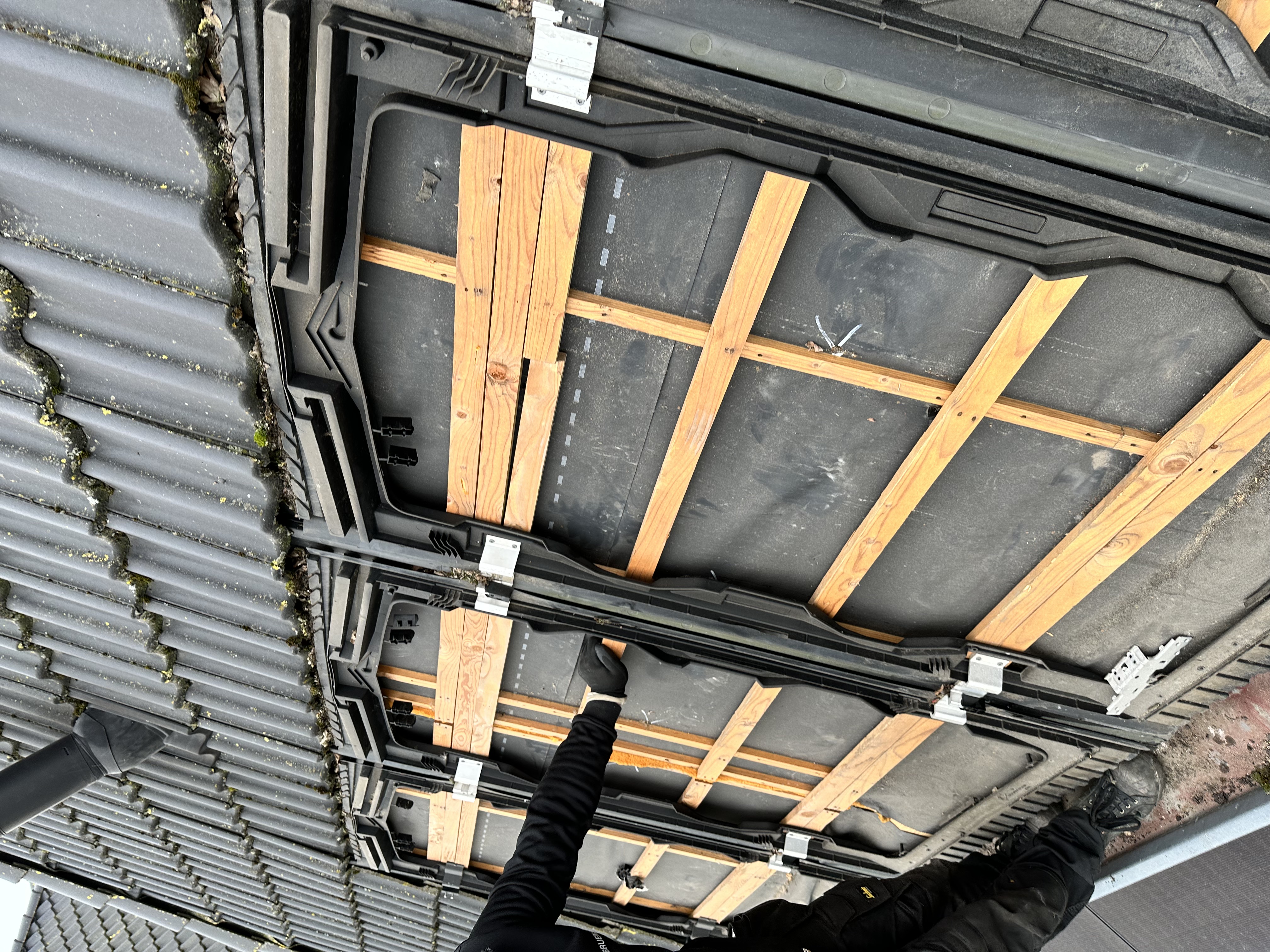 De afbeelding toont een laadpaal installatie met de montagematerialen en een technicus aan het werk.