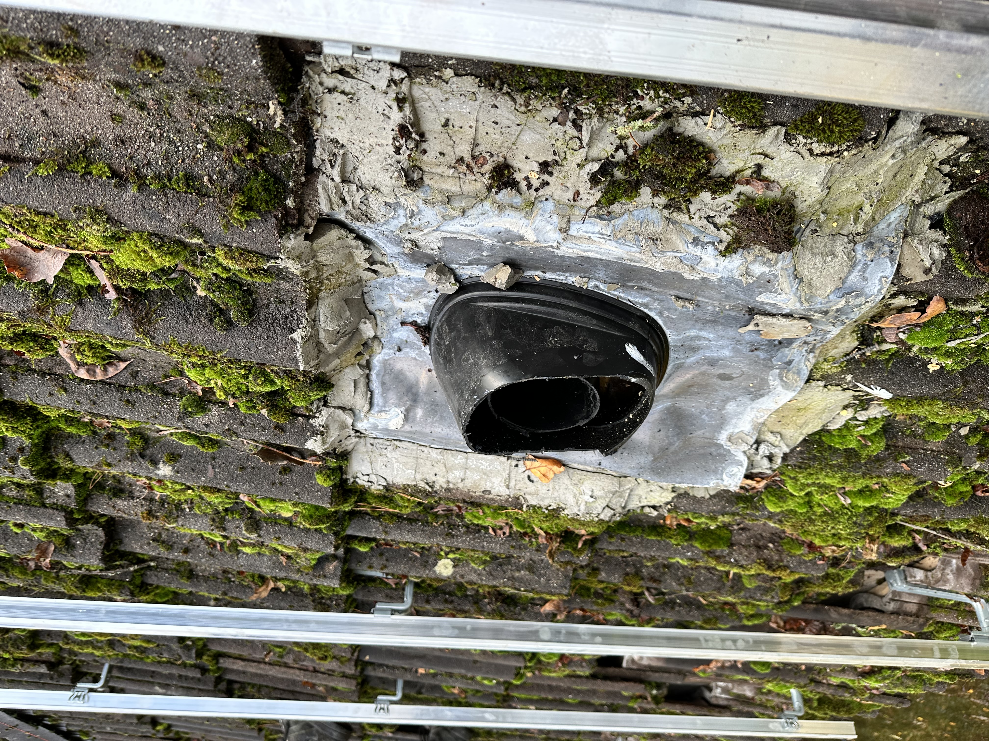 De afbeelding toont een deel van een zonnepaneleninstallatie met montagemateriaal op een dak, waaronder een bevestigingspunt en een doorvoer.