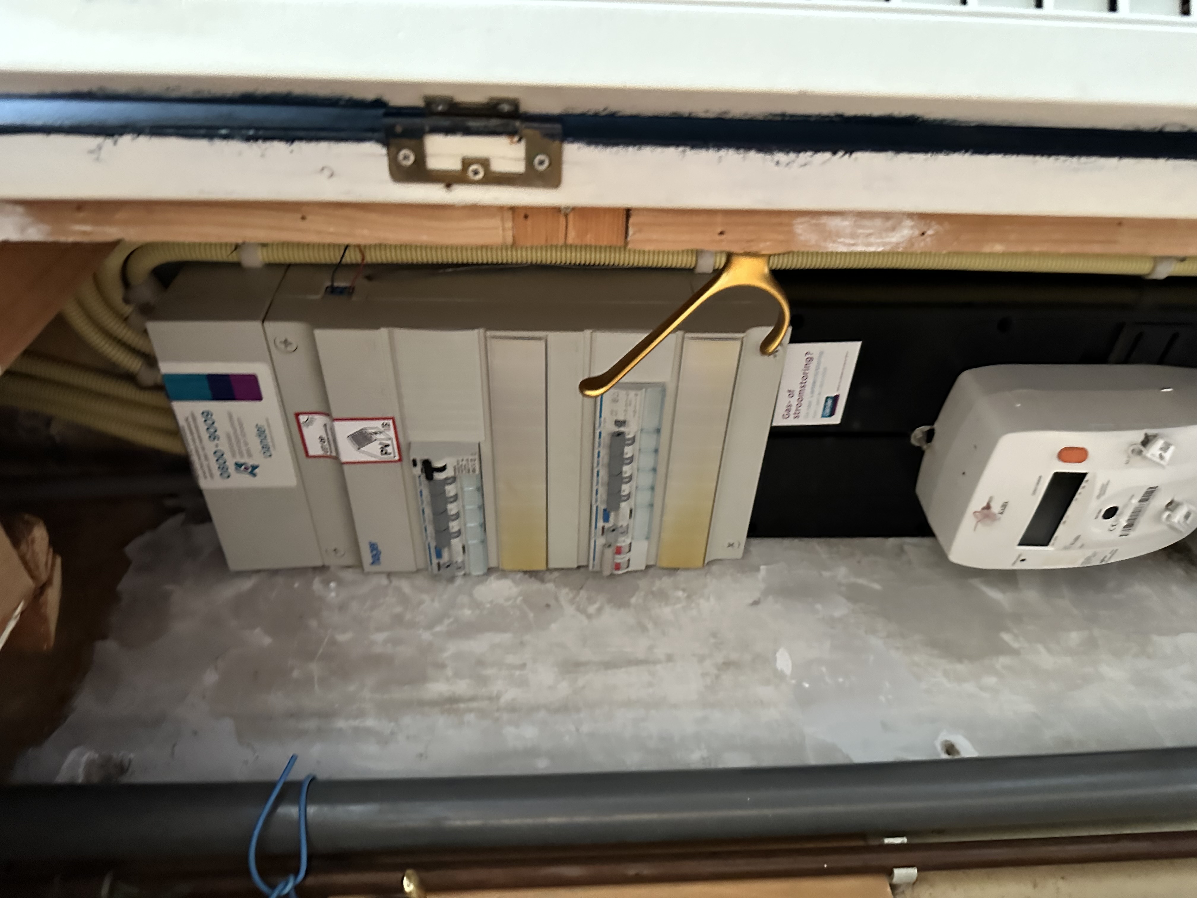 De afbeelding toont een meterkast met elektriciteitsmeters en bekabeling, belangrijk voor de aansluiting van zonnepanelen, maar de zonnepanelen zelf zijn niet zichtbaar.