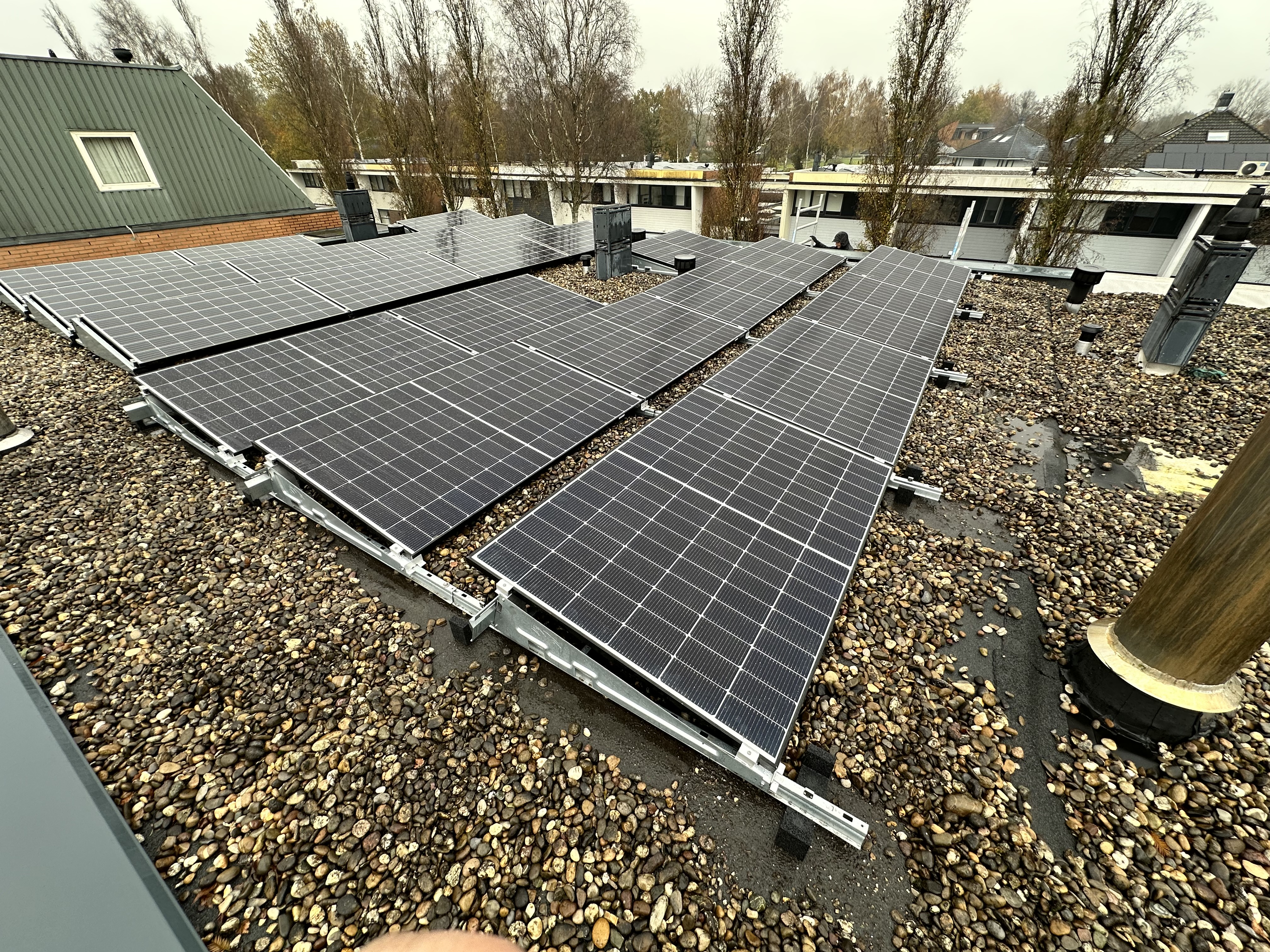 Een installatie van zonnepanelen op een dak, met meerdere panelen die netjes zijn gerangschikt op een grindbediening.