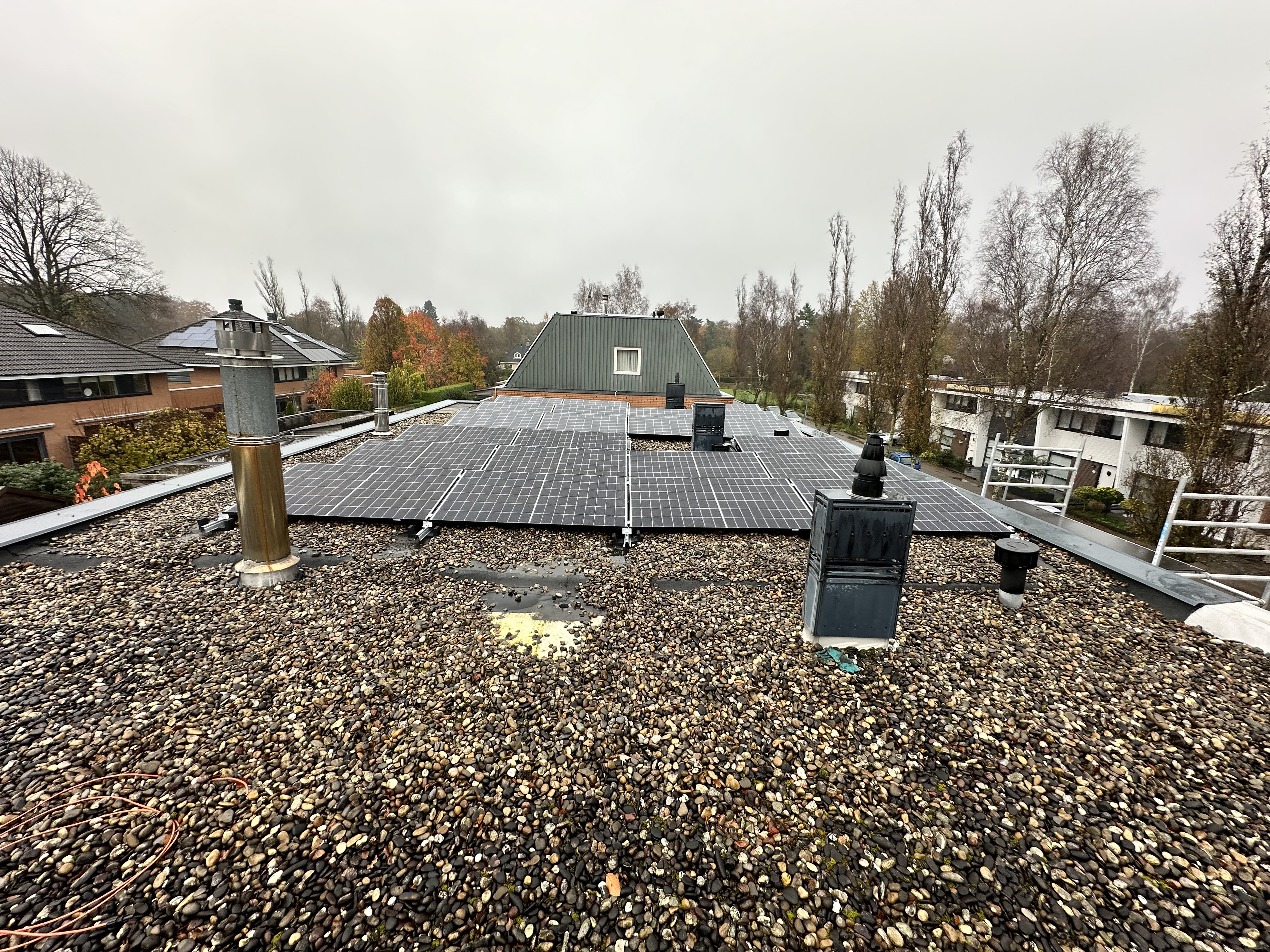 De foto toont zonnepanelen op een plat dak, omringd door grind. De installatie is duidelijk zichtbaar met meerdere panelen die zijn geplaatst.