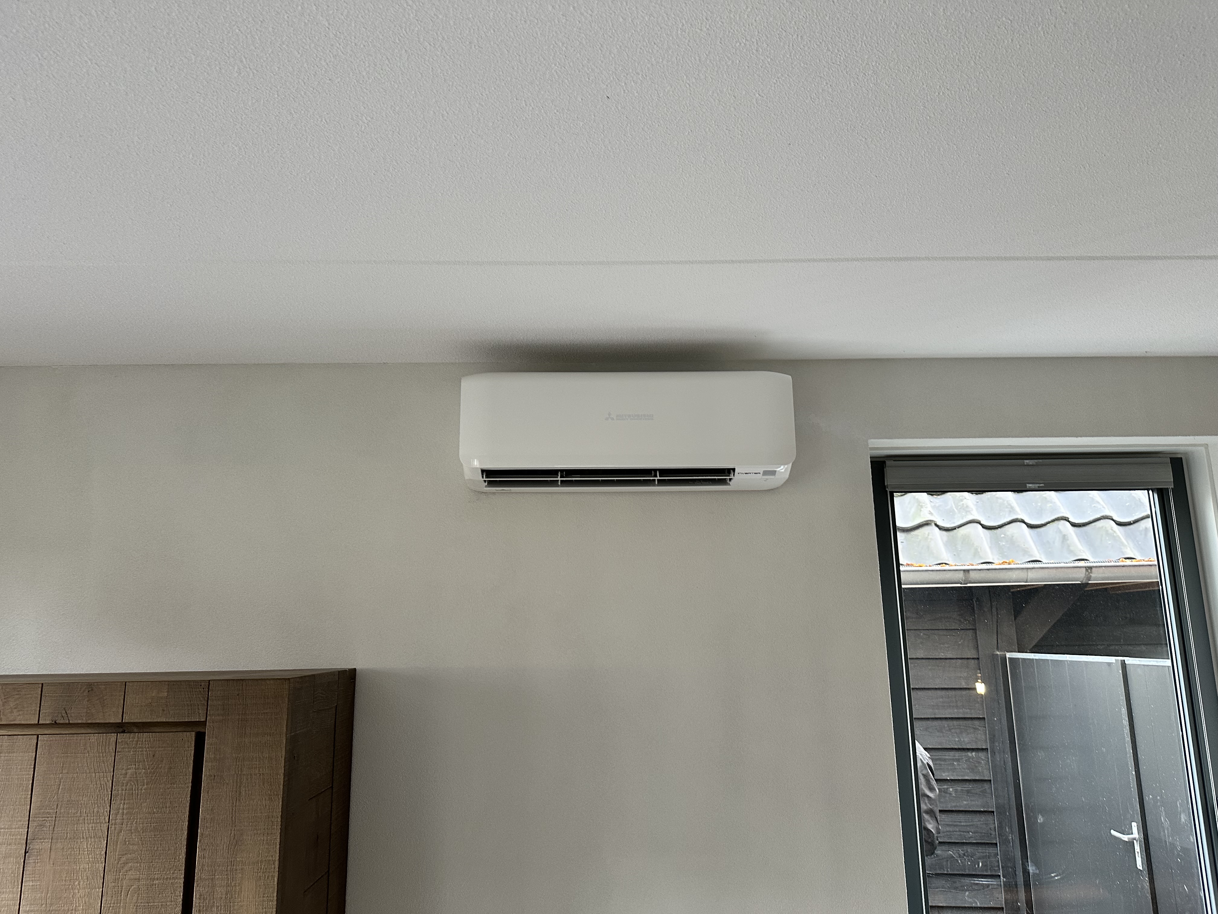 Een moderne airconditioningseenheid is geïnstalleerd aan de muur, ideaal voor het reguleren van de temperatuur in een woonruimte.