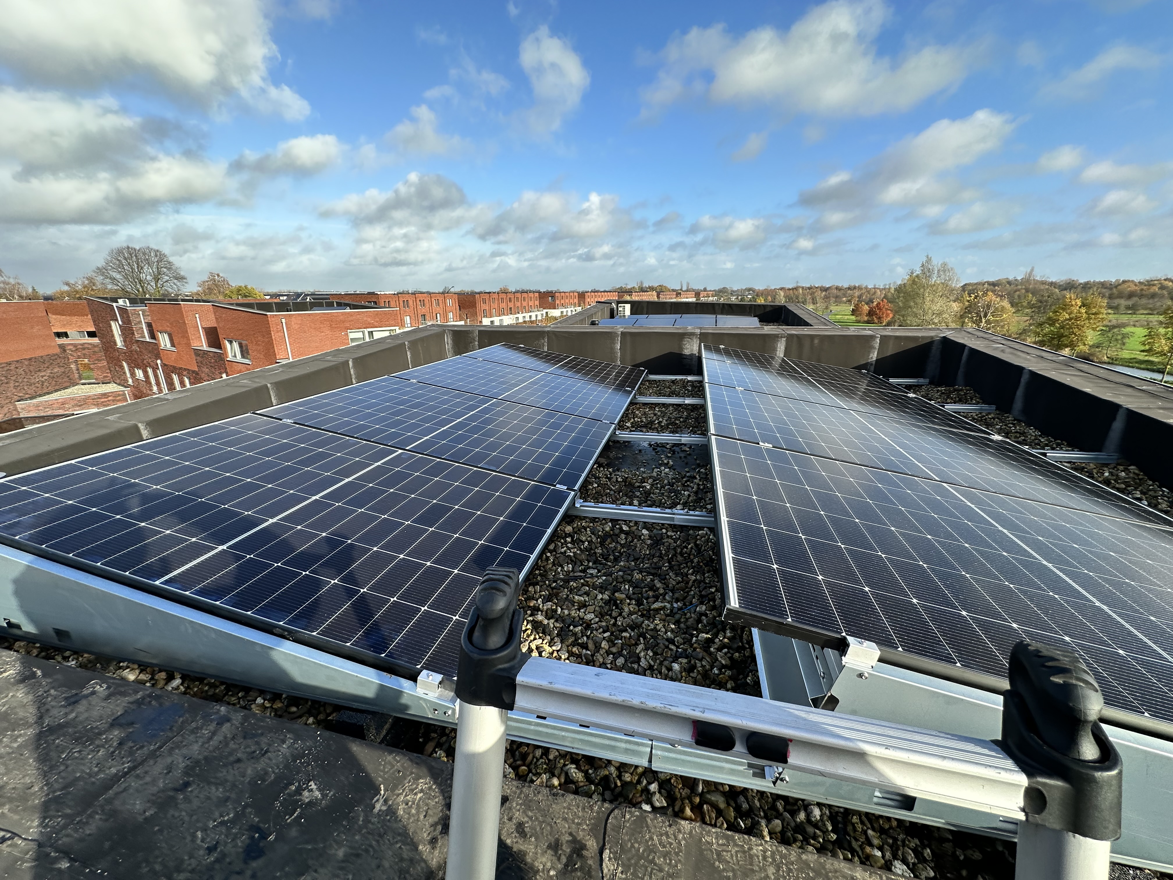 Deze installatie toont zonnepanelen die zijn geplaatst op een plat dak, omringd door grind voor stabiliteit.