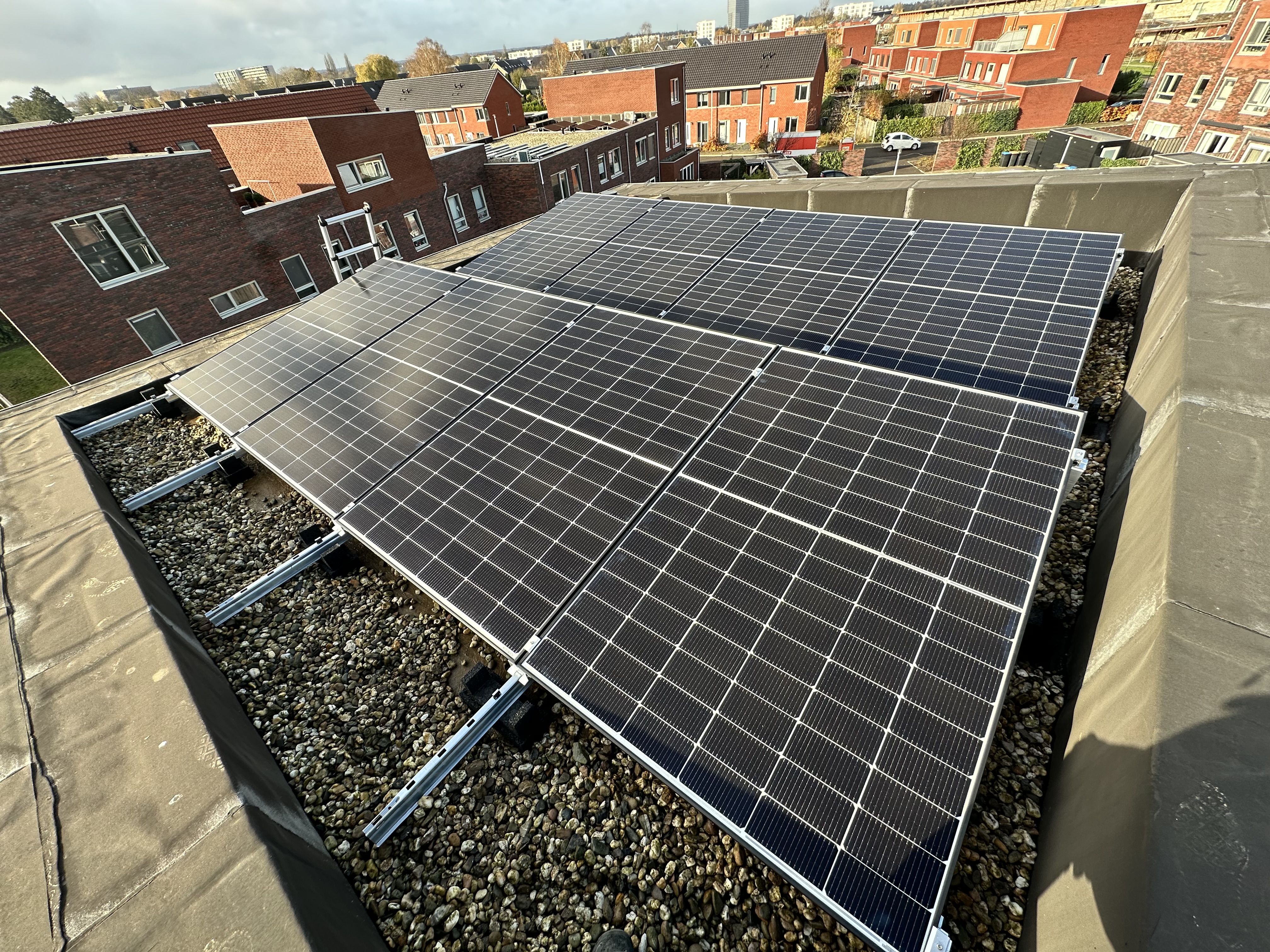 Deze installatie toont een reeks zonnepanelen op een plat dak, netjes geïnstalleerd met een steenslagbed.