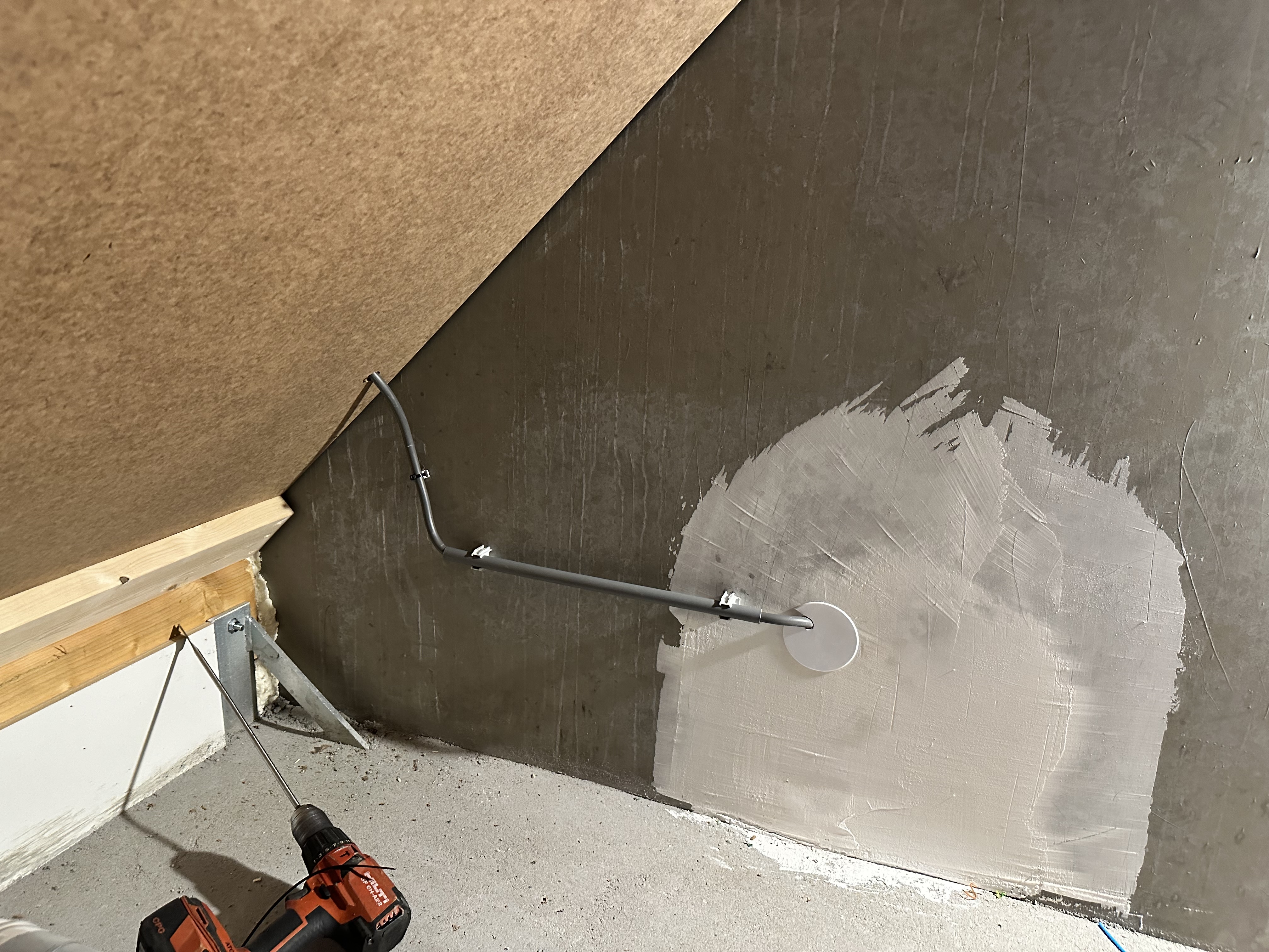 De afbeelding toont een aansluitpunt voor zonnepanelen, met een metallic buis en bevestigingsmateriaal in een werkomgeving.