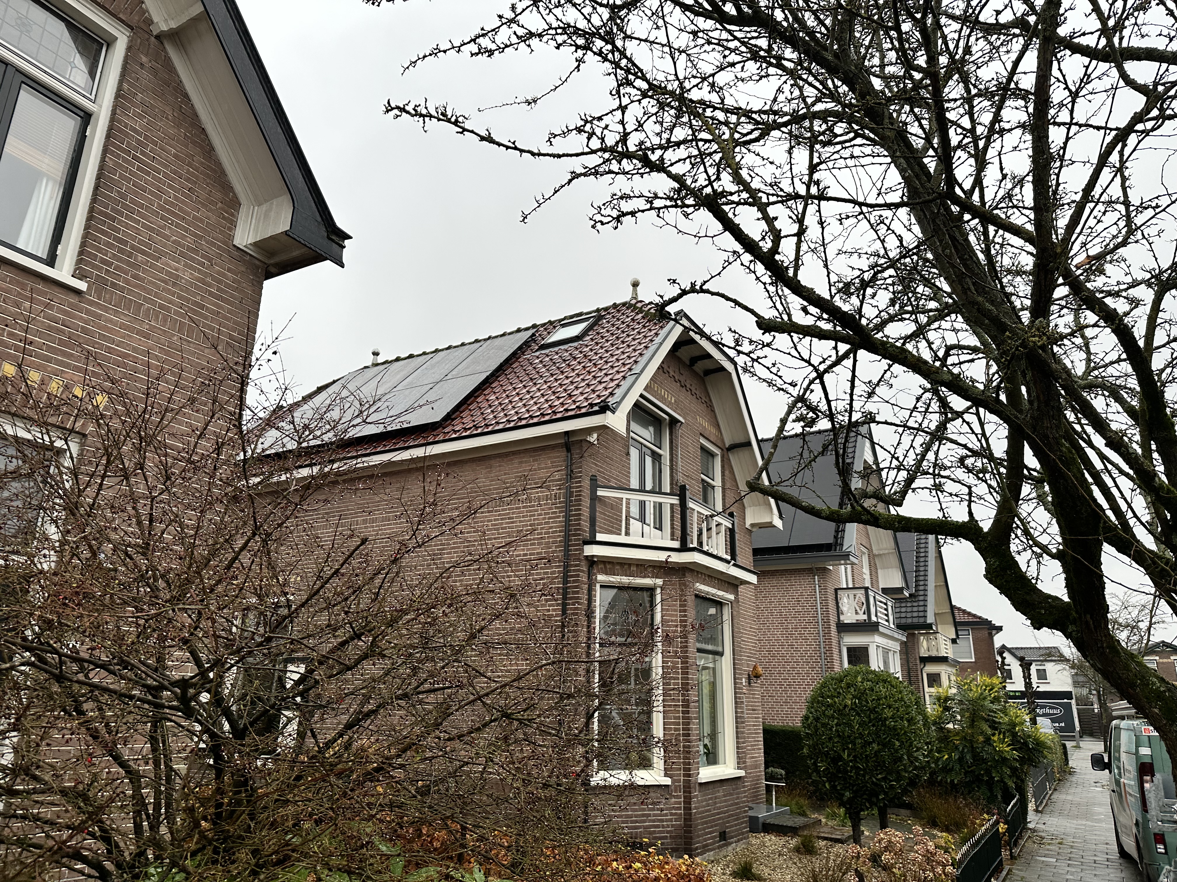 Zonnepanelen zijn geïnstalleerd op het dak van een woning, zichtbaar in een stedelijke omgeving met een dreigende lucht.