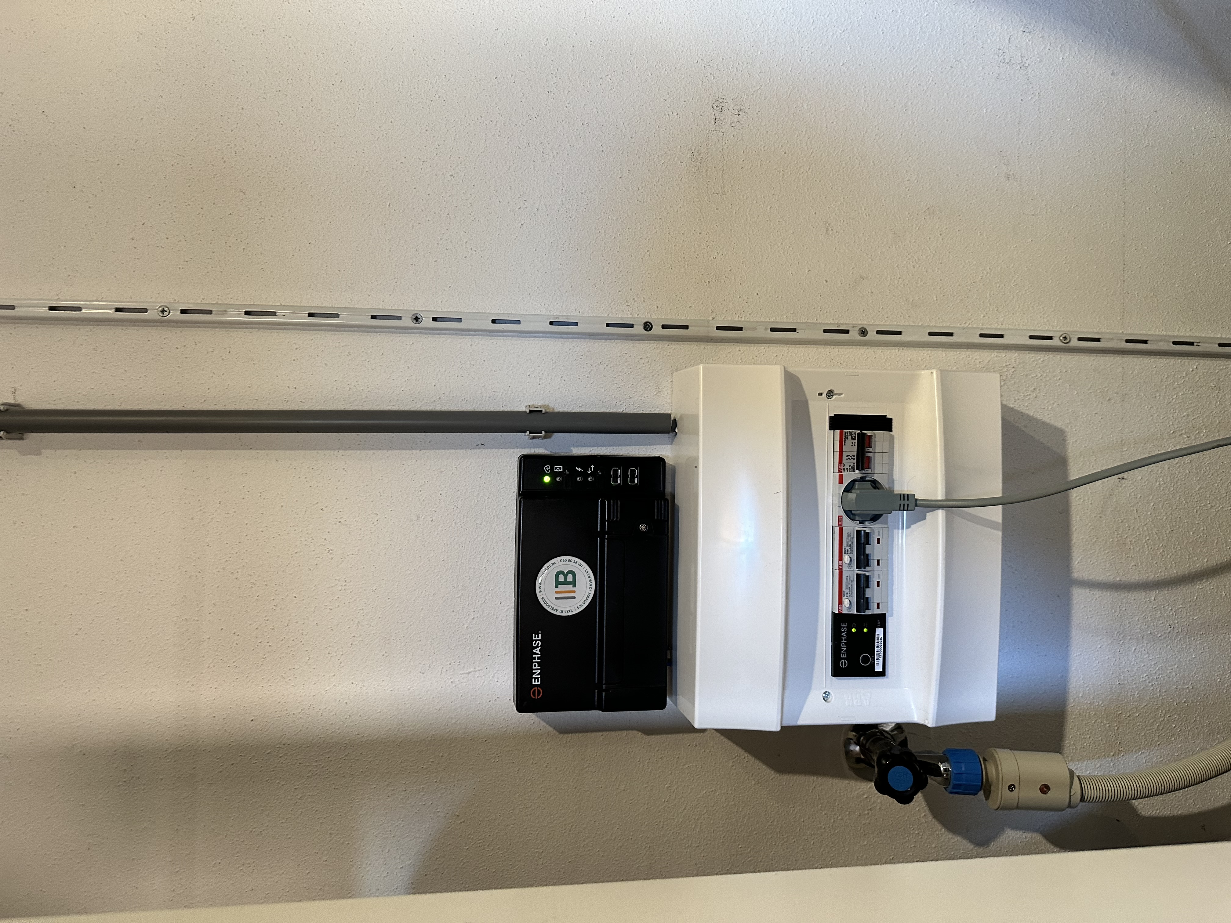De afbeelding toont een omvormer en meterkast die behoren tot een zonnepanelen installatie. Deze componenten zijn essentieel voor het omzetten van zonne-energie naar gebruiksklare stroom.