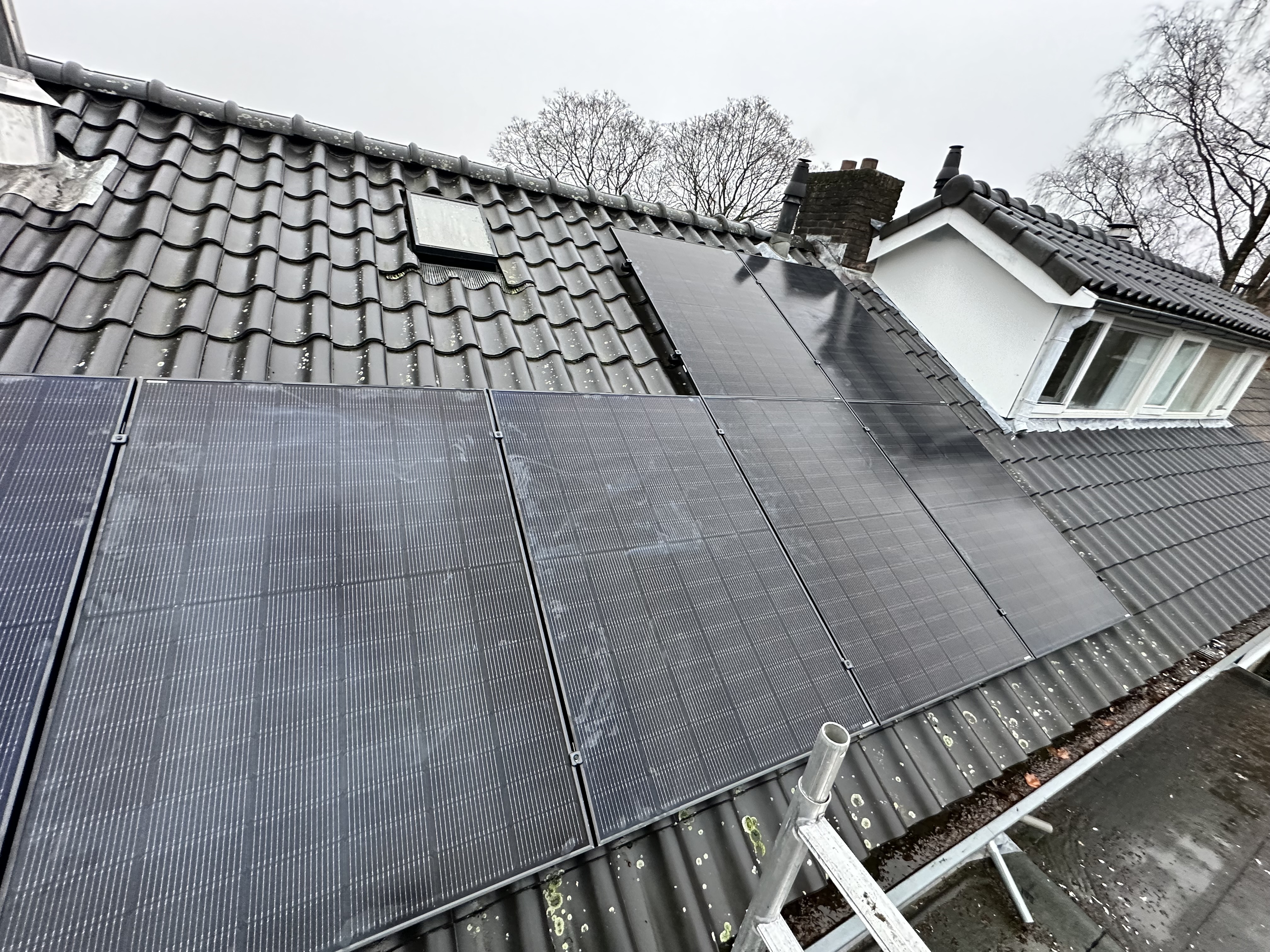 Een installatie van zonnepanelen op een dak met een helling. De panelen zijn zichtbaar en goed positioneerd voor zonlicht.