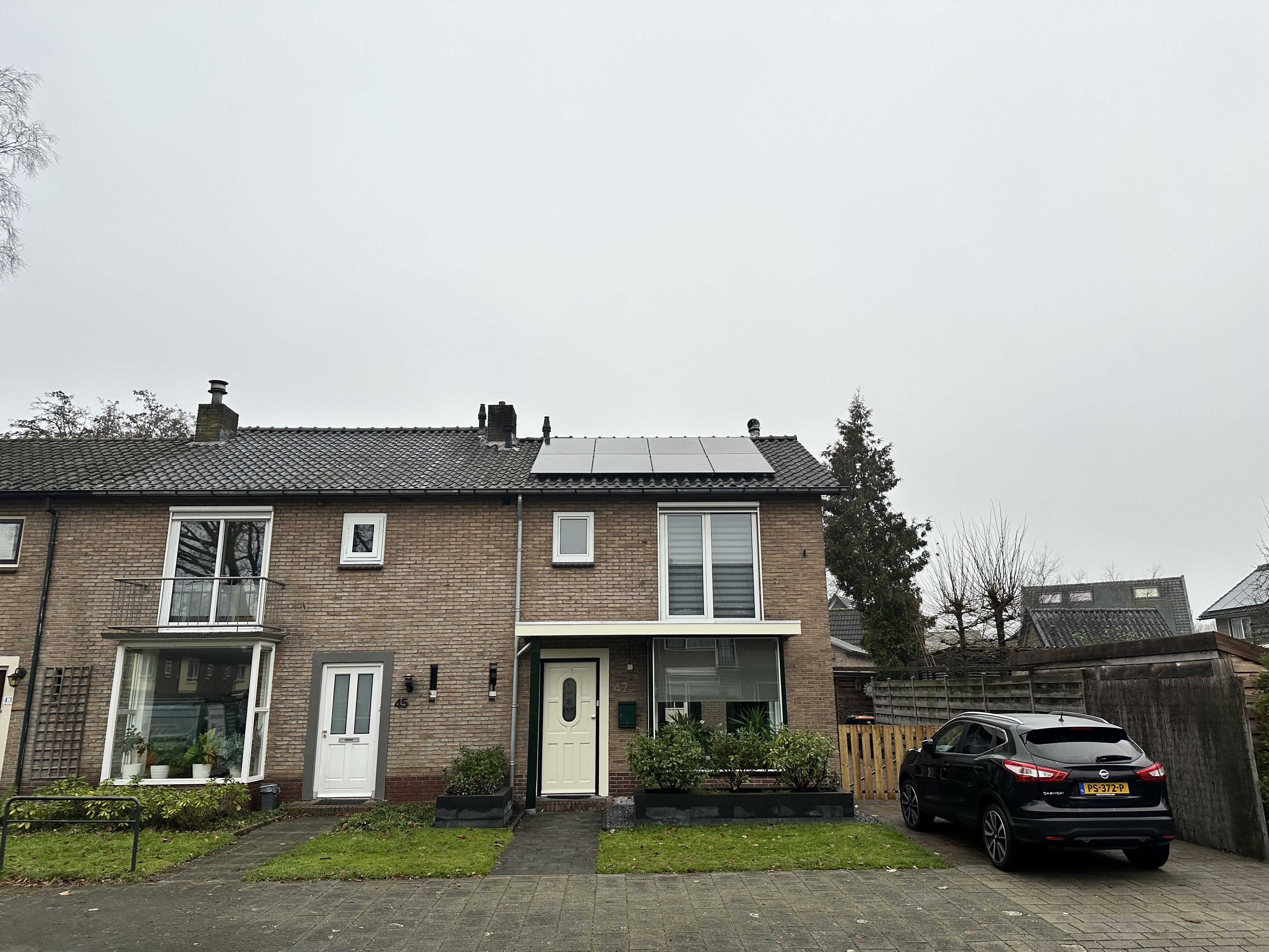 Zonnepanelen zijn geïnstalleerd op het dak van een woning, wat wijst op gebruik van hernieuwbare energie.