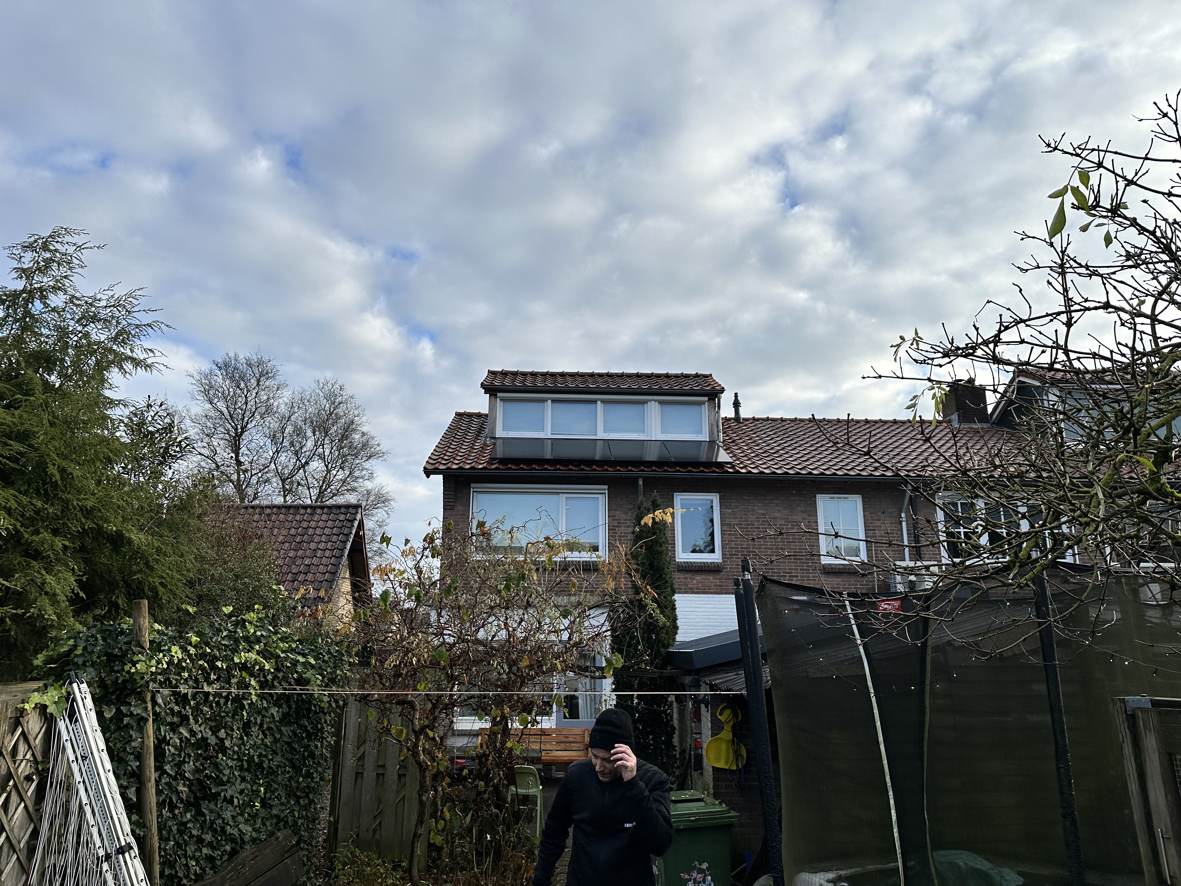 De foto toont een woning met zonnepanelen op het dak, geïnstalleerd in een residentiële omgeving.