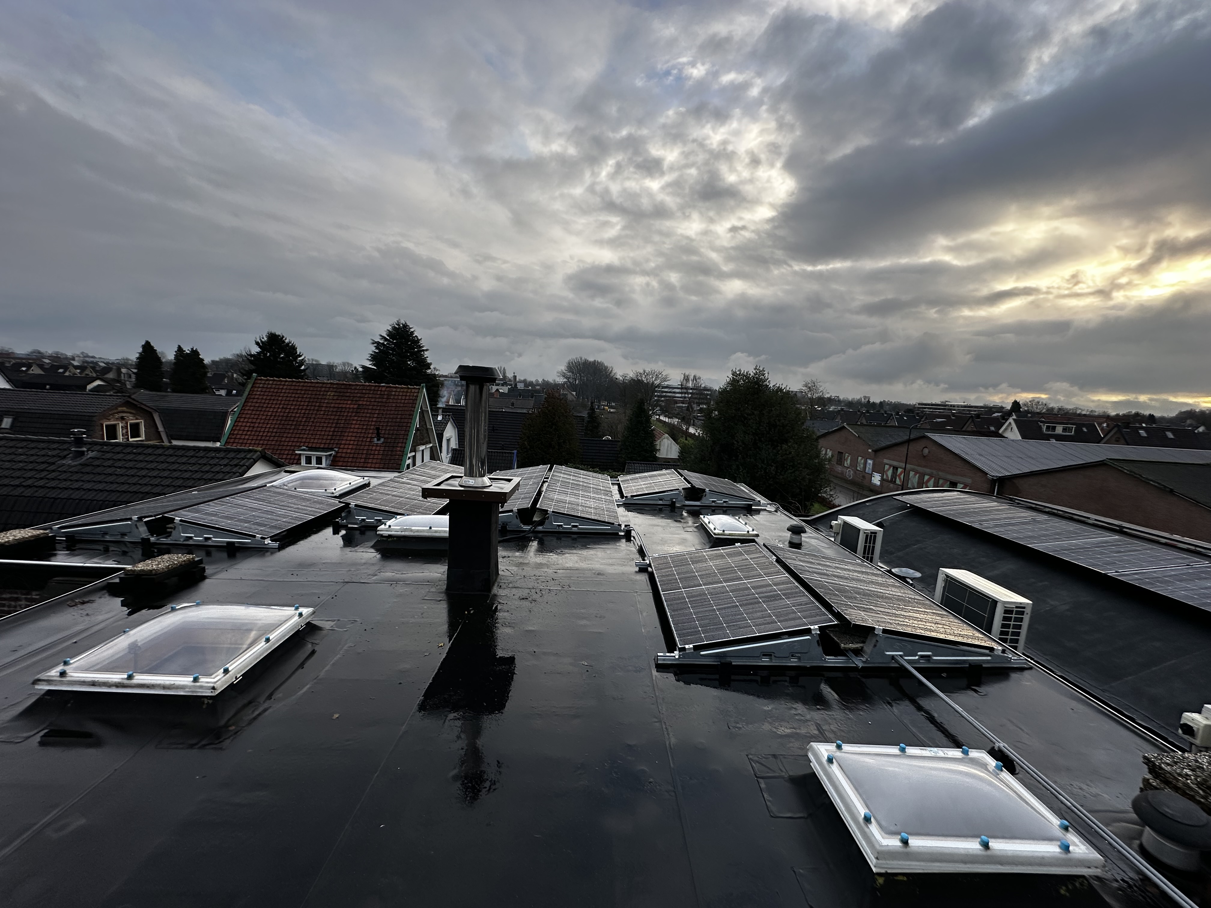 De foto toont een installatie van zonnepanelen op een plat dak, met meerdere panelen uitgelijnd om optimale zonne-energie te verzamelen.