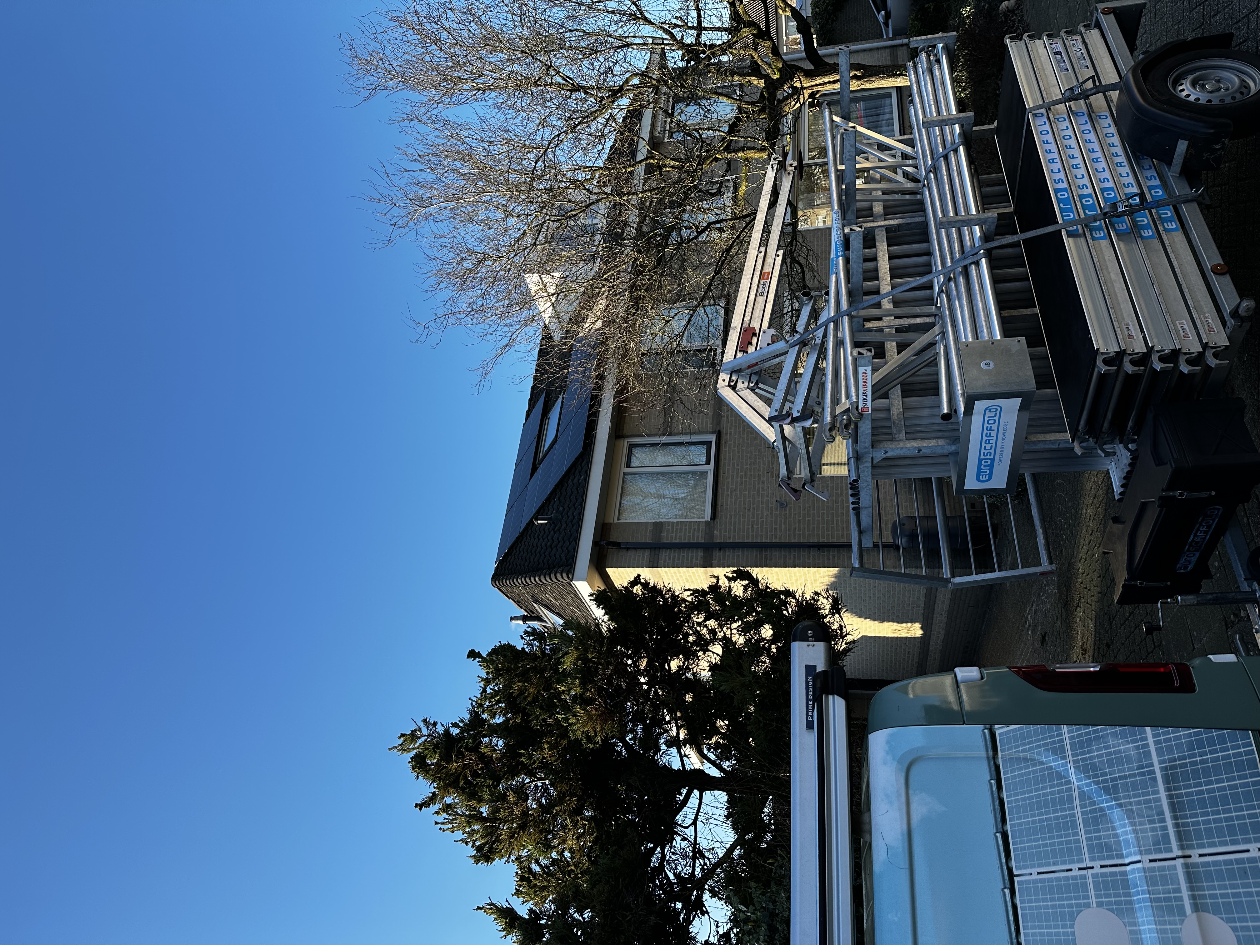 Zonnepanelen zijn geïnstalleerd op een dak, met een heldere blauwe lucht op de achtergrond.