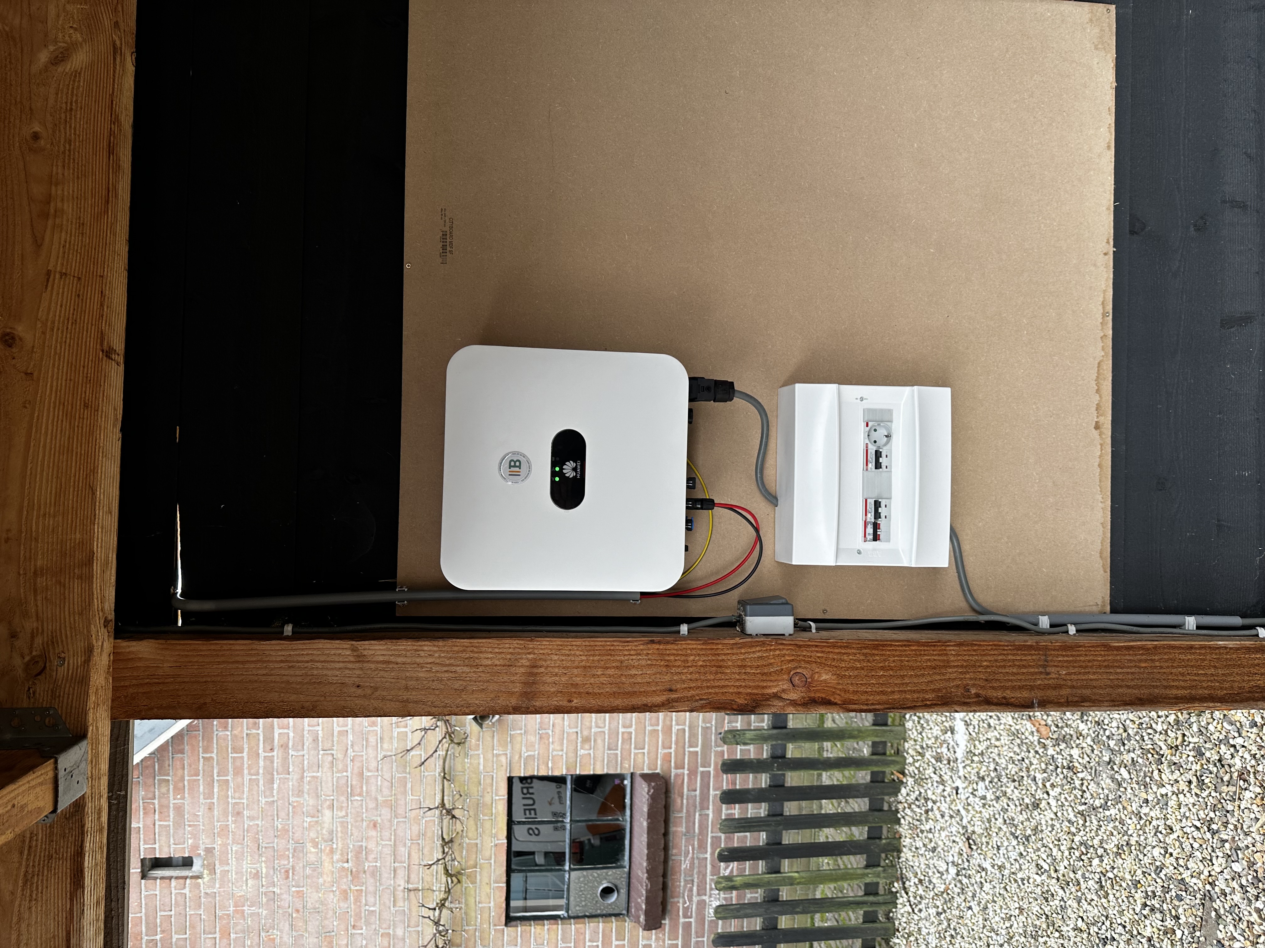 De afbeelding toont een omvormer die onderdeel is van een zonnepanelen-installatie, voorzien van bekabeling en een aansluiting voor netvoedsel.
