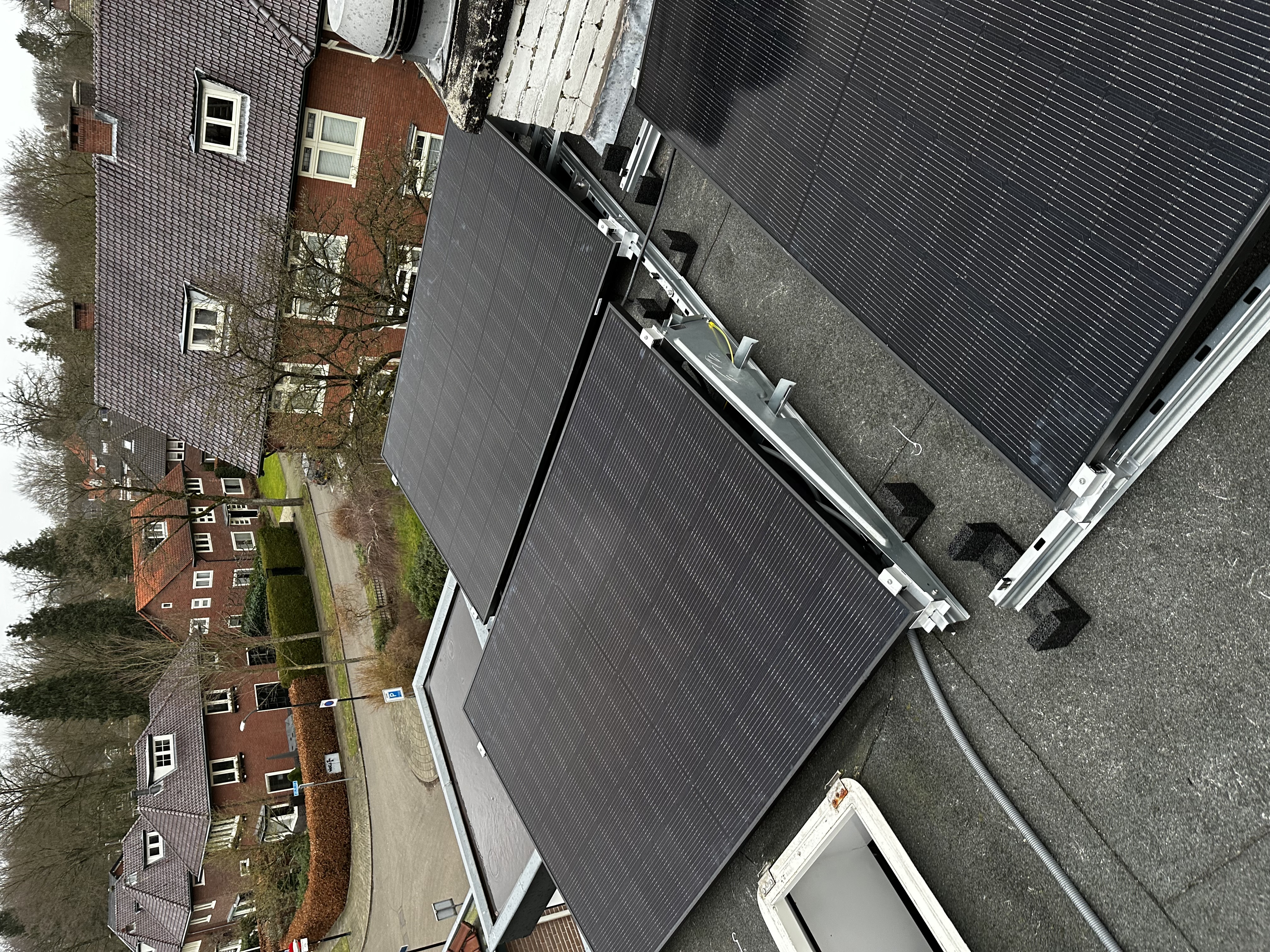 De afbeelding toont een installatie van zonnepanelen op een dak, met meerdere panelen verbonden via een montagesysteem.