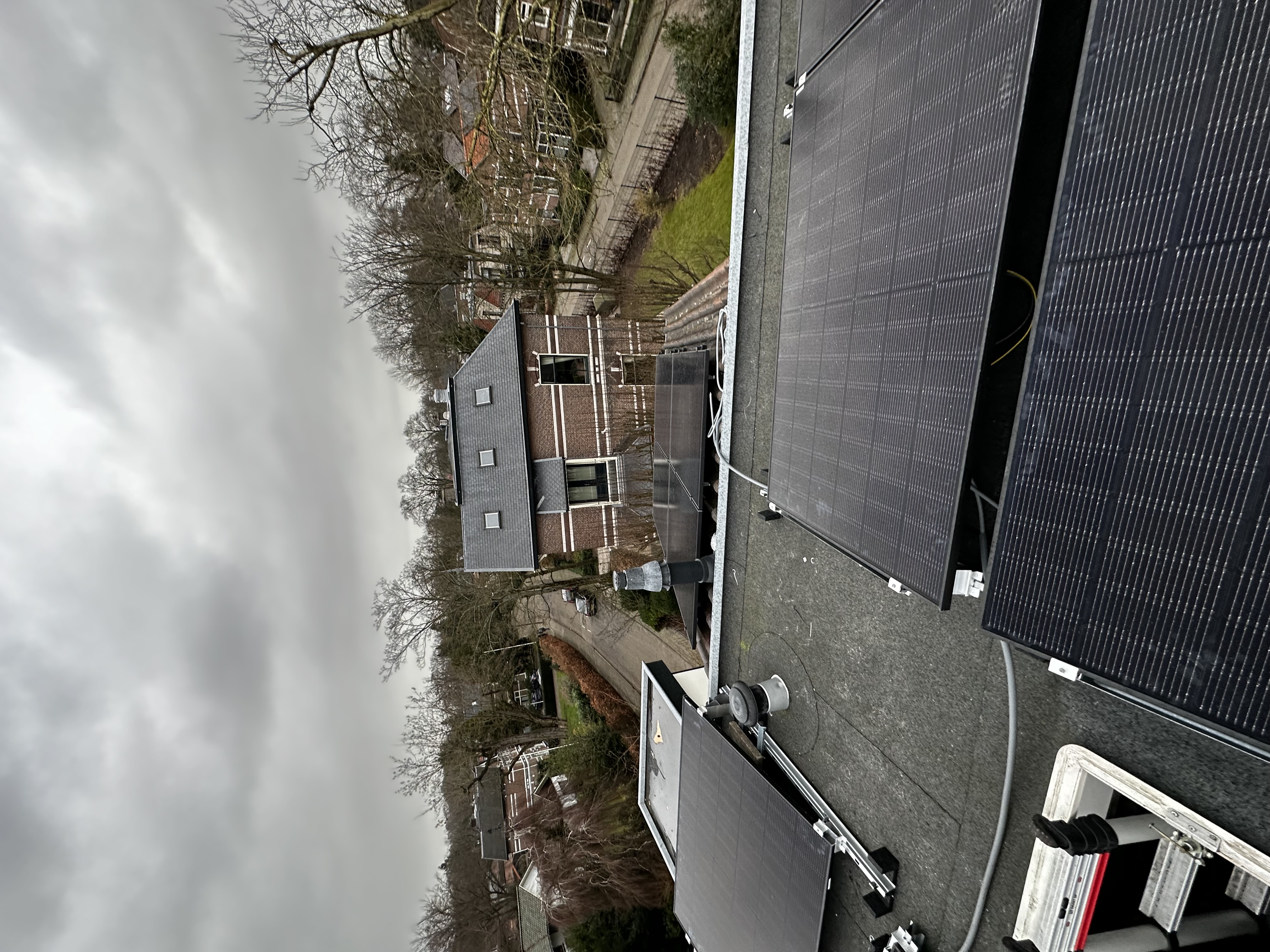 Installatie van zonnepanelen op een dak, zichtbaar met zonnepanelen en een deel van de omgeving.