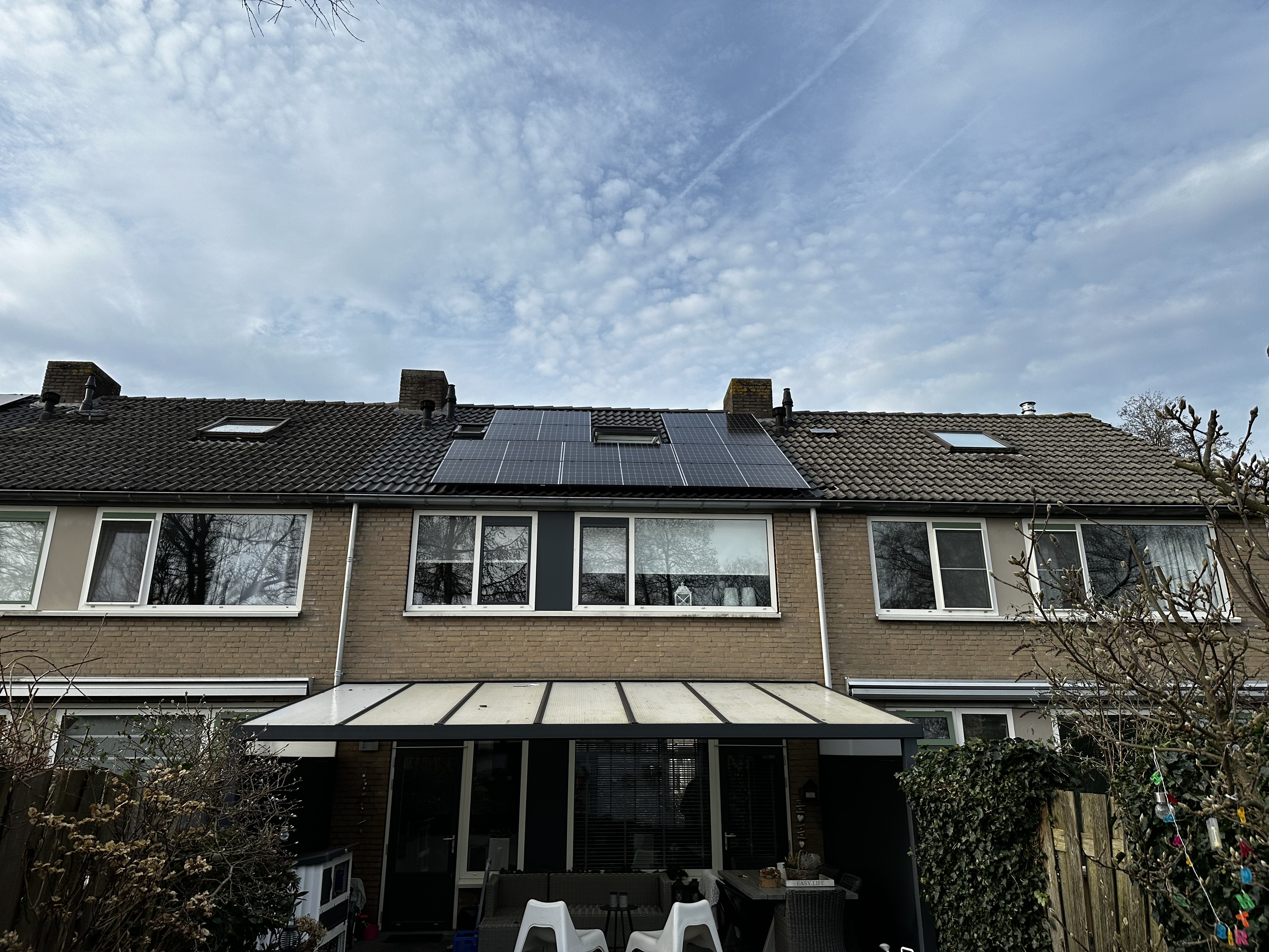 De installatie toont zonnepanelen op het dak van een rijtjeshuis, optimaal gepositioneerd voor zonlicht.