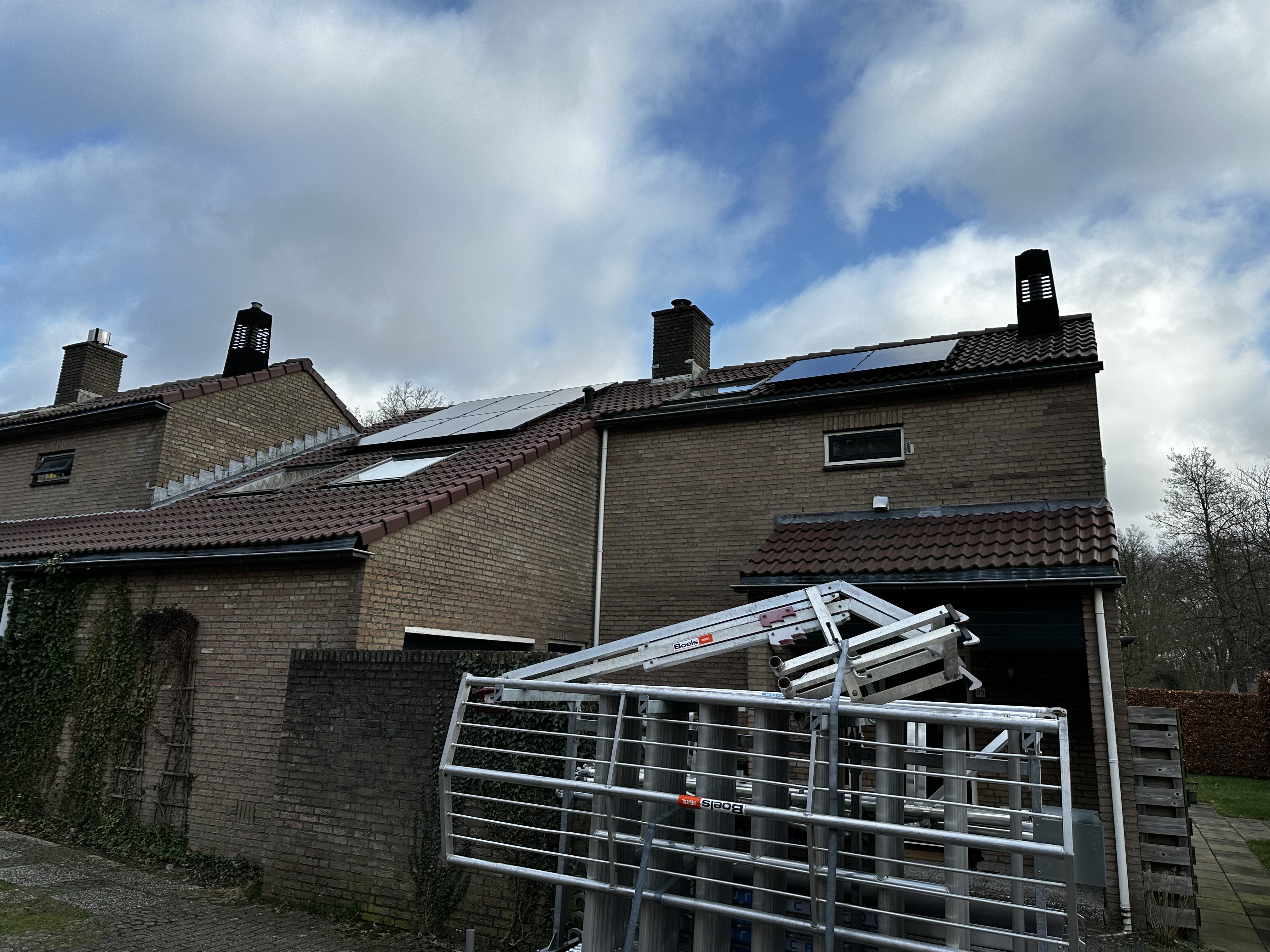 De afbeelding toont zonnepanelen geïnstalleerd op het dak van een woning, met een heldere lucht op de achtergrond.
