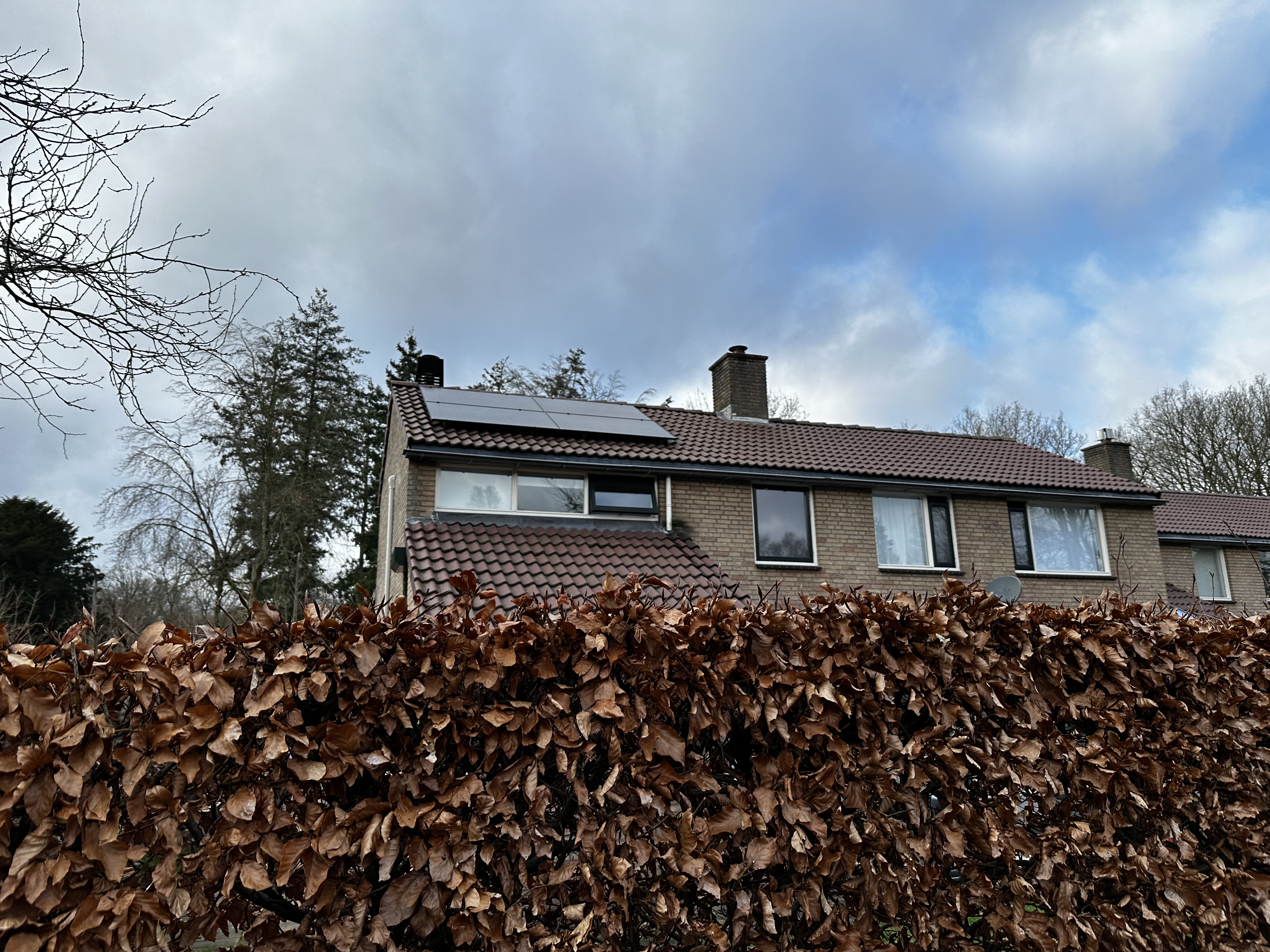 De foto toont een woning met zonnepanelen op het dak, geïntegreerd in de dakconstructie.
