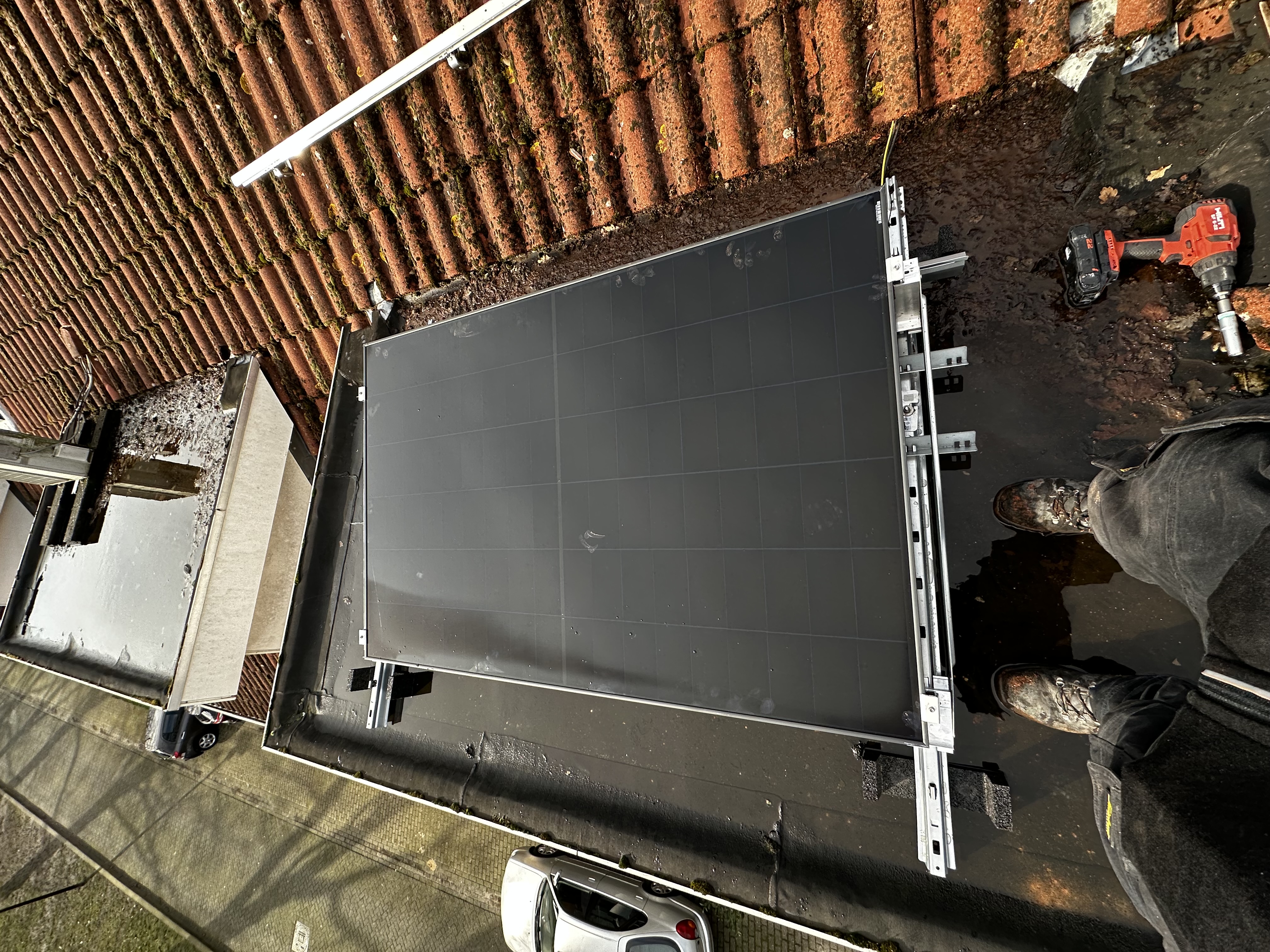 De installatie toont zonnepanelen die op een hellend dak zijn geplaatst, met gereedschap zichtbaar voor de montage.