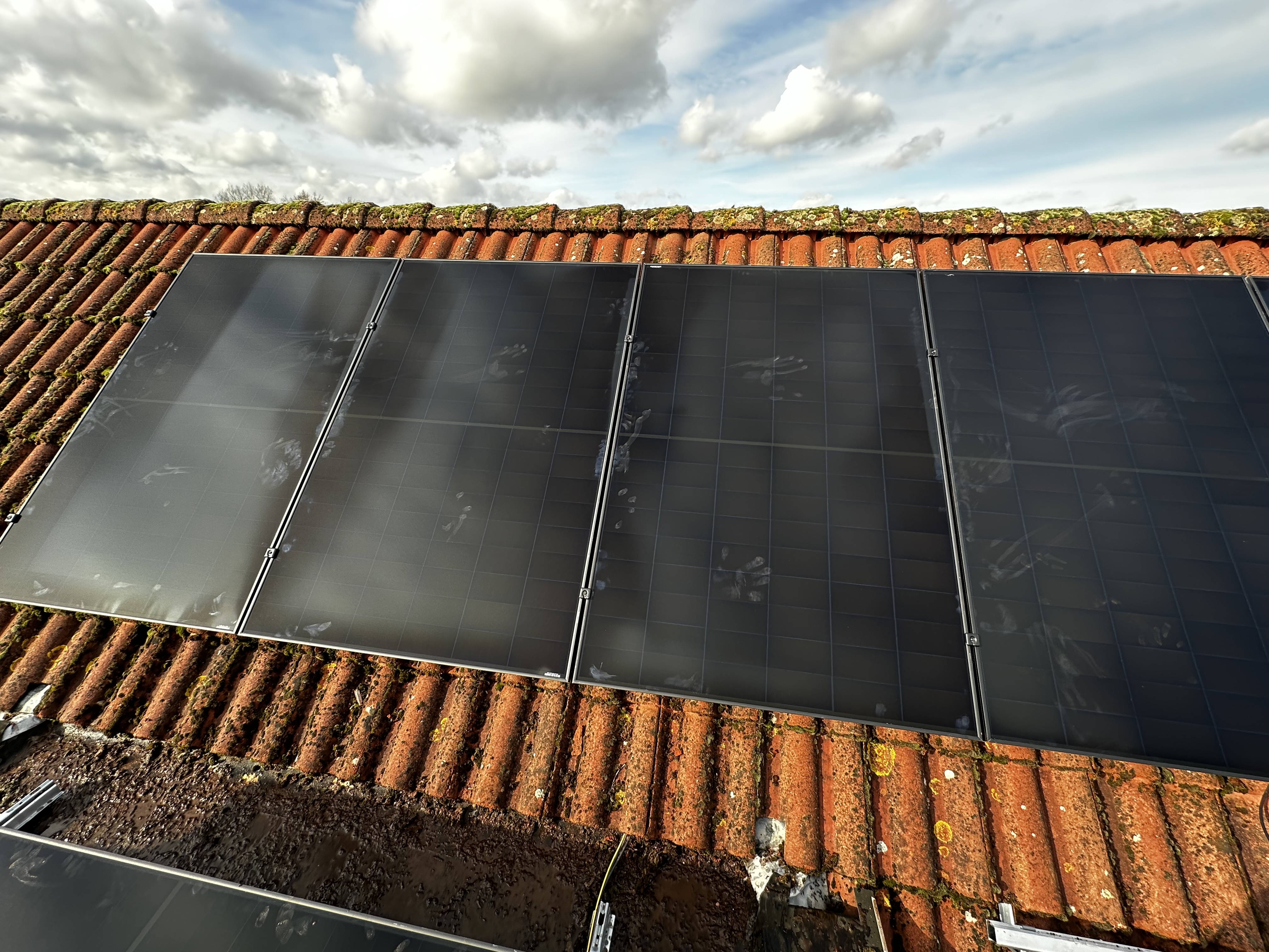 Een montage van zonnepanelen op een schuin dak, zichtbaar met de omliggende dakpannen.