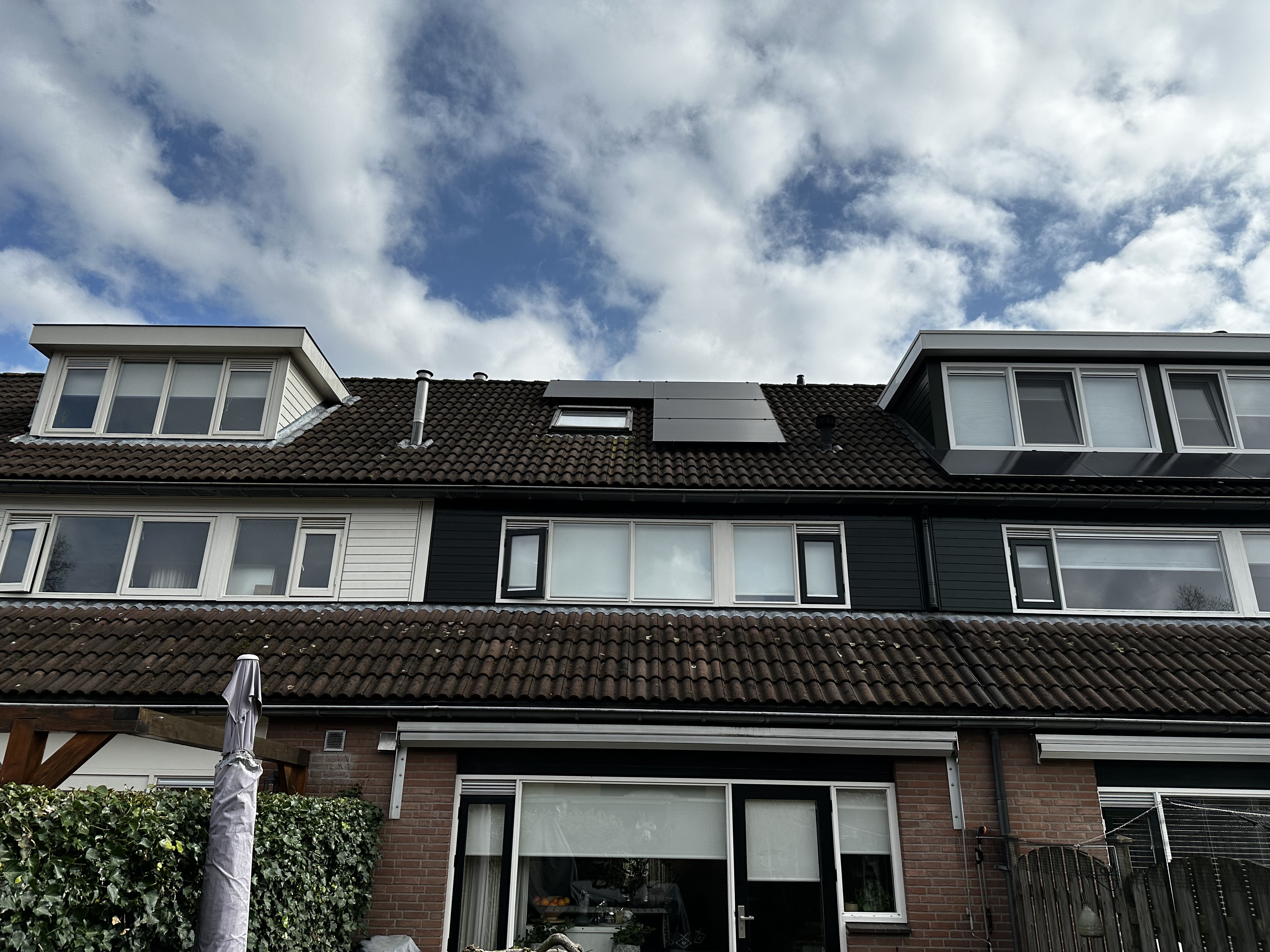 De afbeelding toont zonnepanelen die zijn geïnstalleerd op het dak van een woning, goed zichtbaar in de context van de huisarchitectuur.