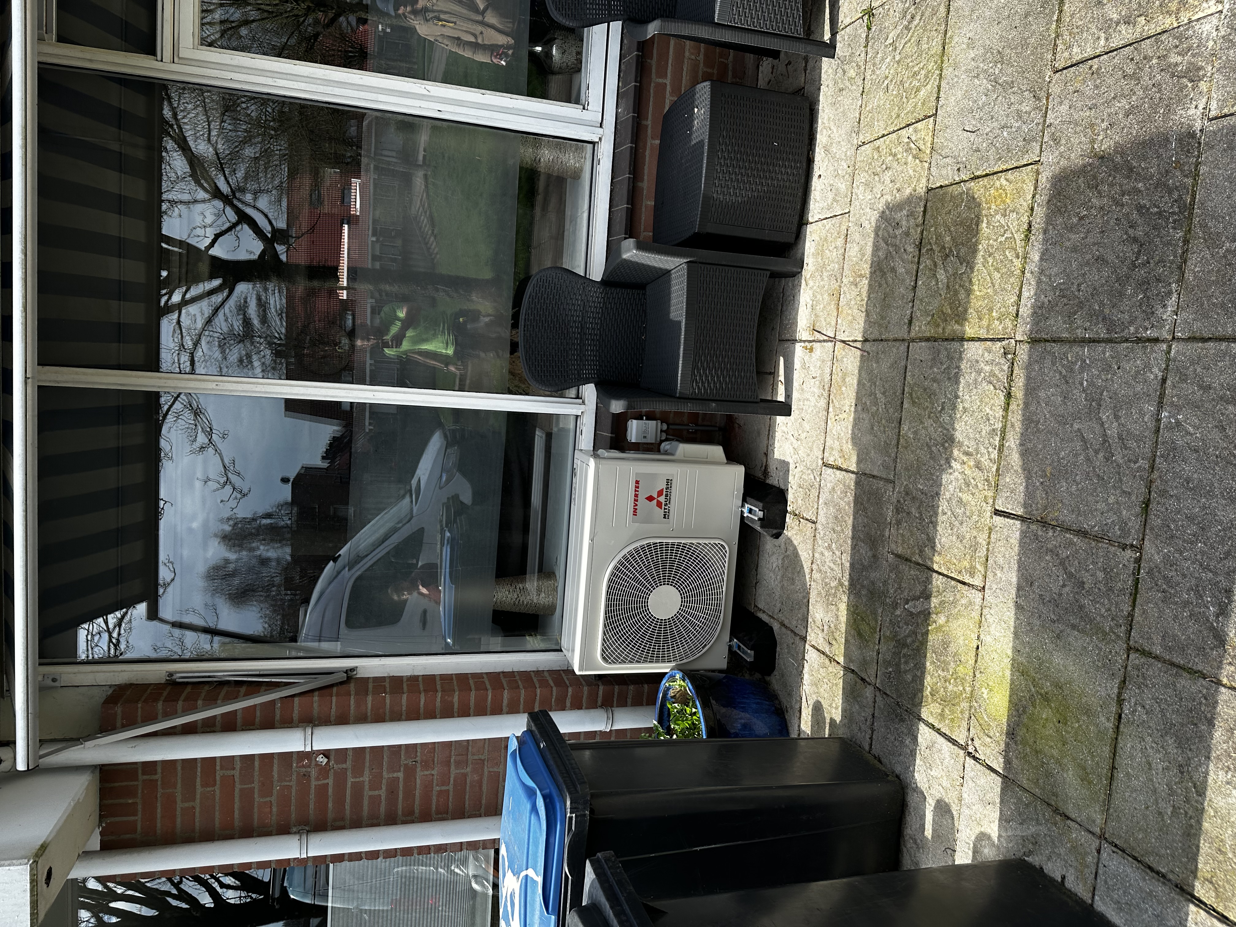 Een airconditioningsysteem is geïnstalleerd buiten, met zichtbare eenheid en leidingen, klaar voor gebruik.