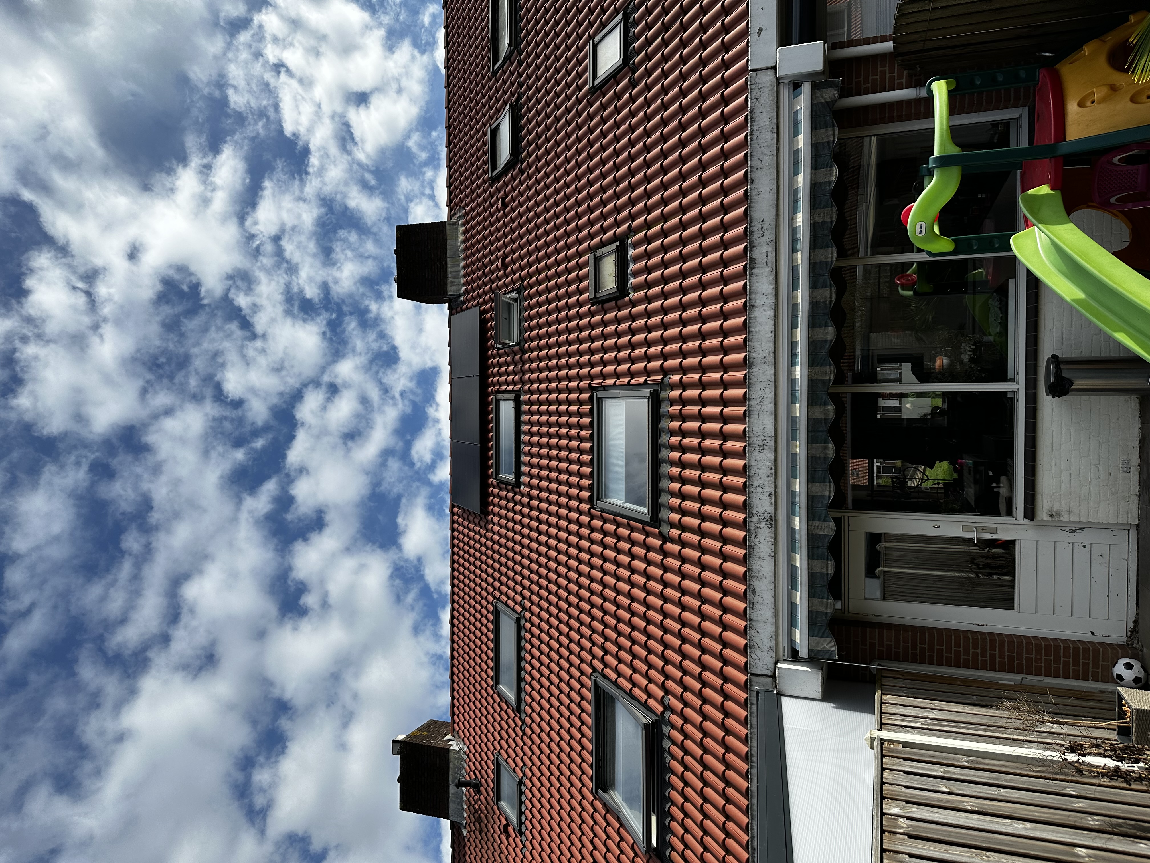 De foto toont een woning met zonnepanelen op het dak, deels in de schaduw van wolken.