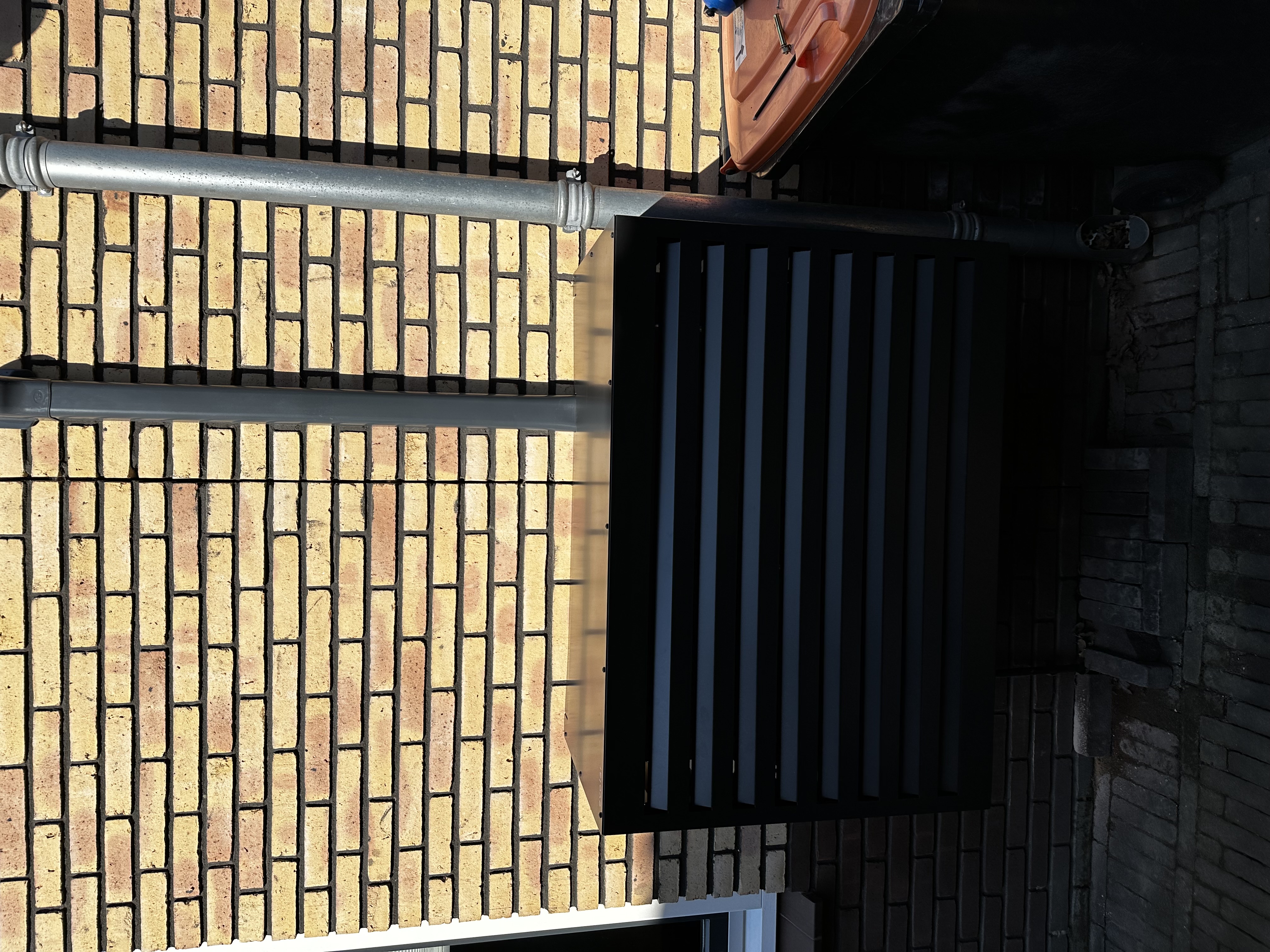 Een buitenunit van een airconditioning systeem, geïnstalleerd tegen een bakstenen muur.