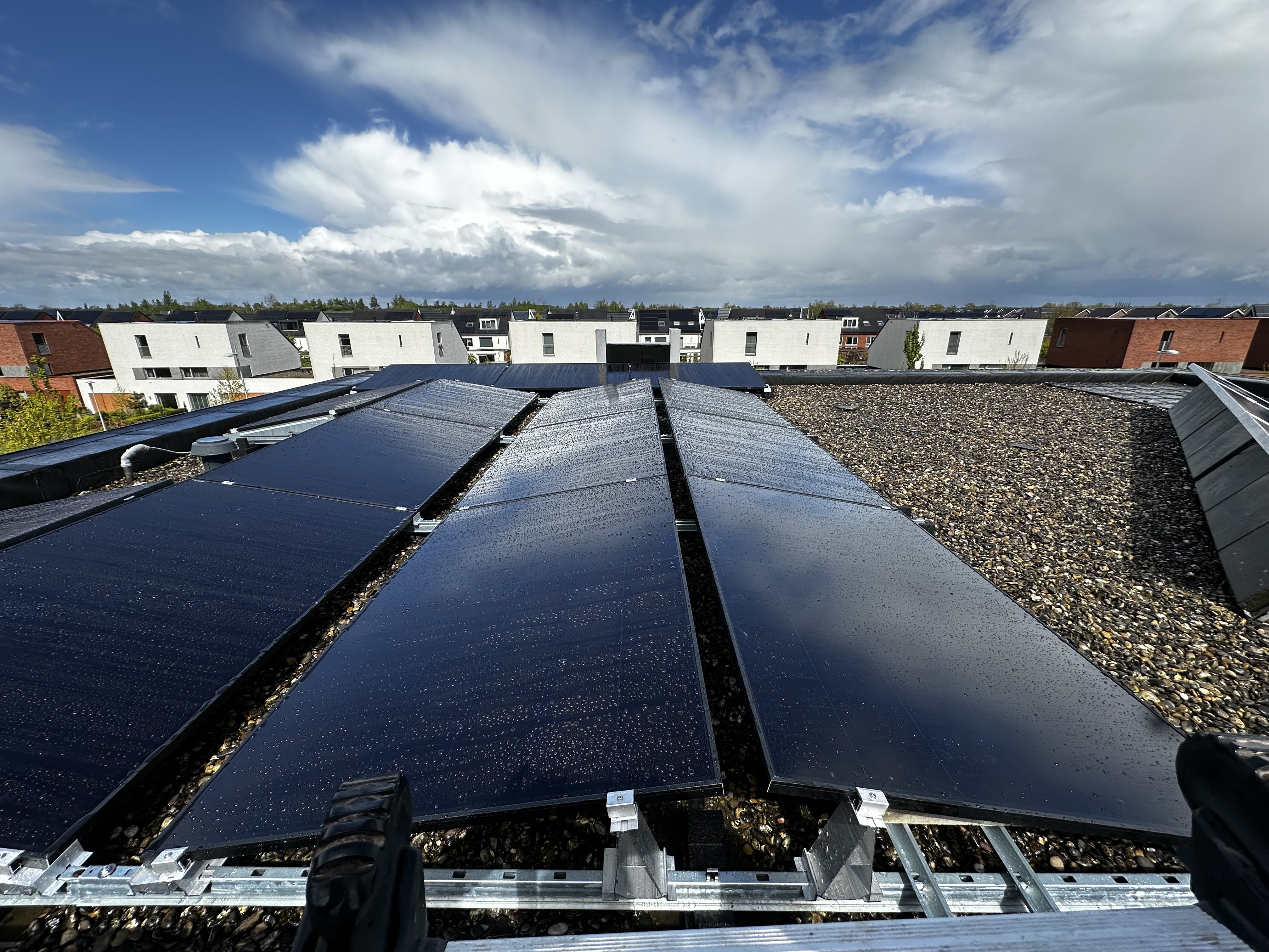 Een installatie van zonnepanelen op een plat dak, zichtbaar met waterdruppels, wat aangeeft dat ze recent zijn gereinigd of dat het geregend heeft.