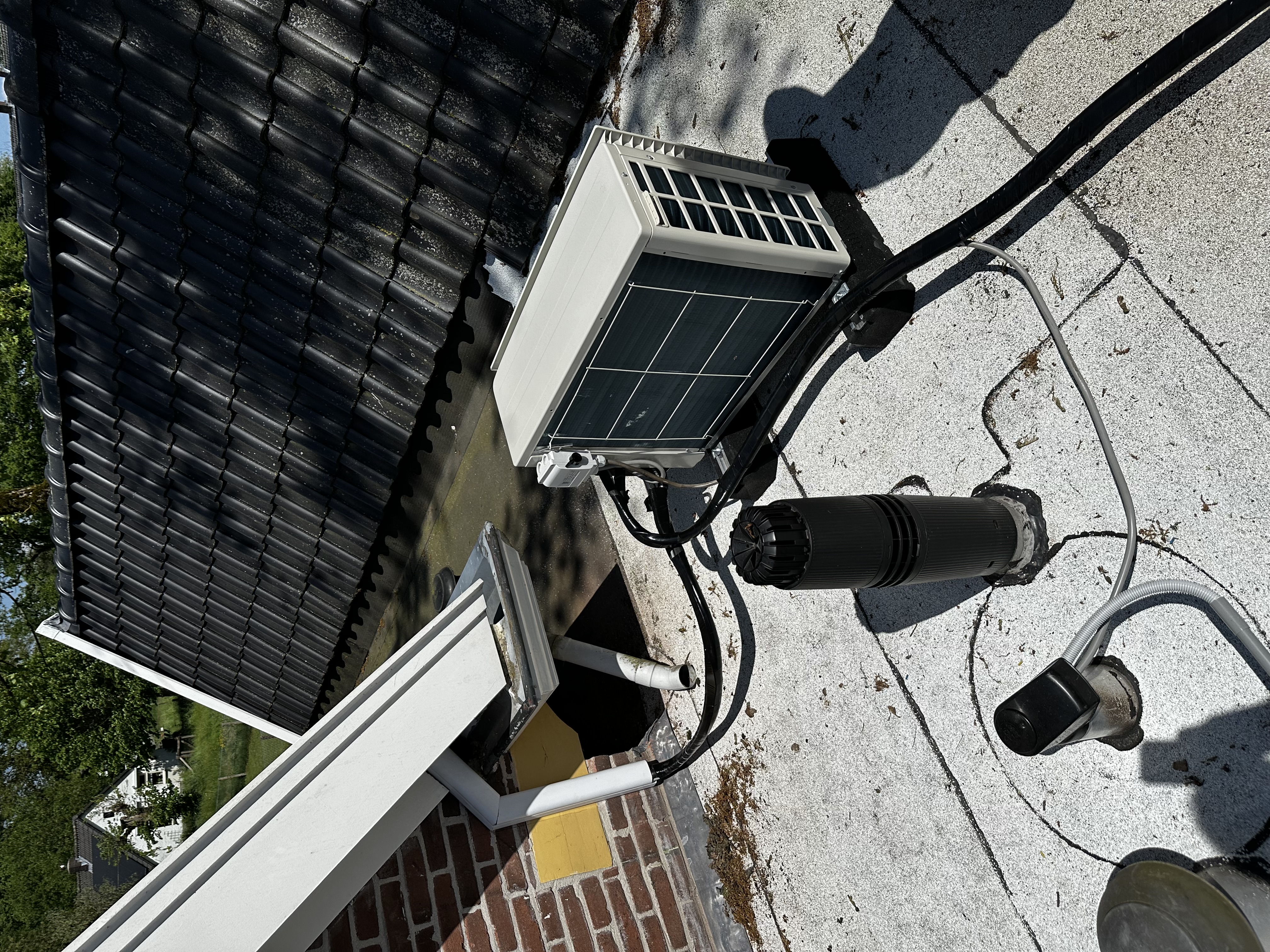 Een airconditioninginstallatie op het dak met leidingen en een buitenunit, klaar voor gebruik.