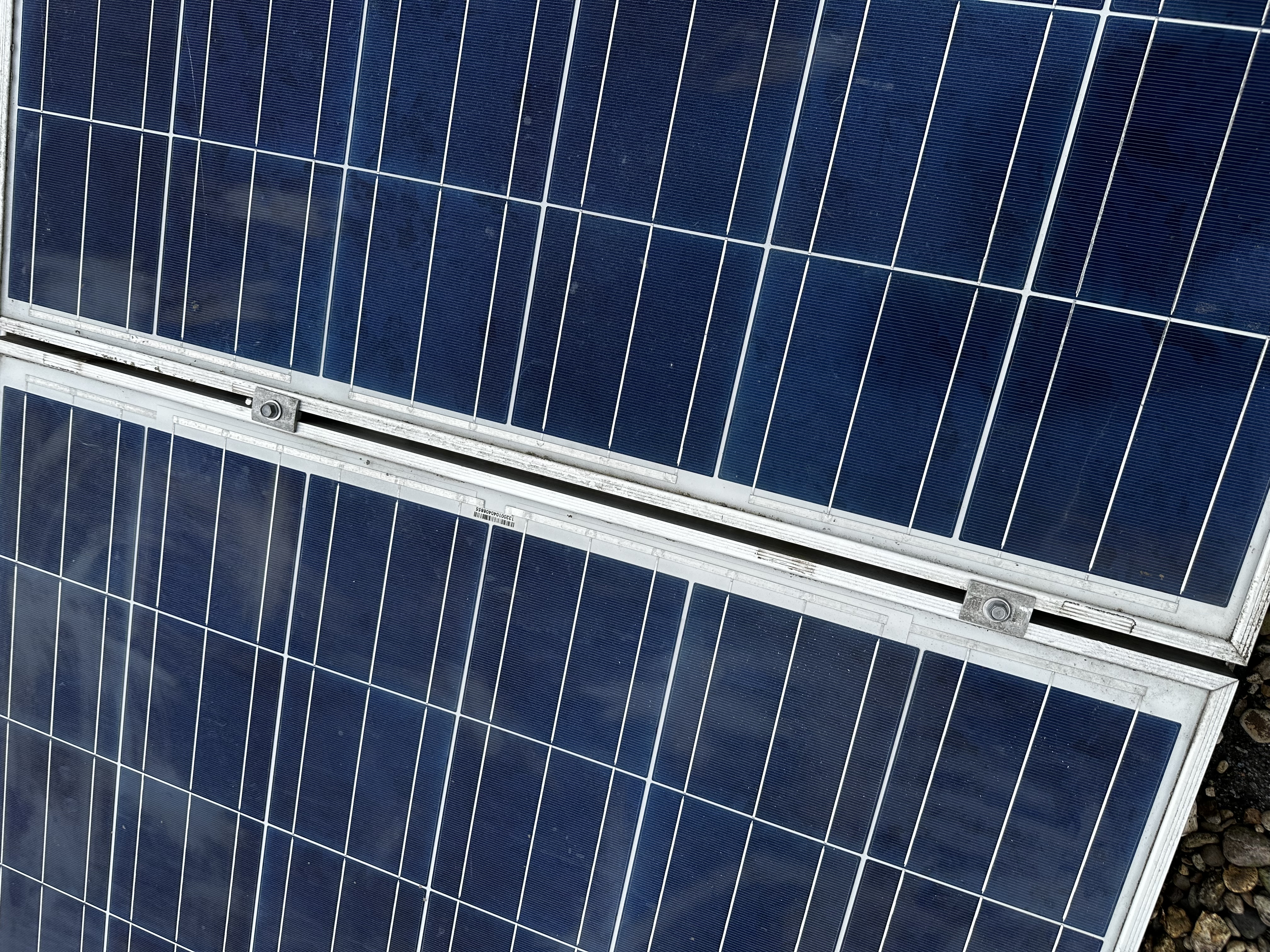 De afbeelding toont een close-up van zonnepanelen met blauwe cellen, duidelijk zichtbaar geïnstalleerd op een ondergrond.