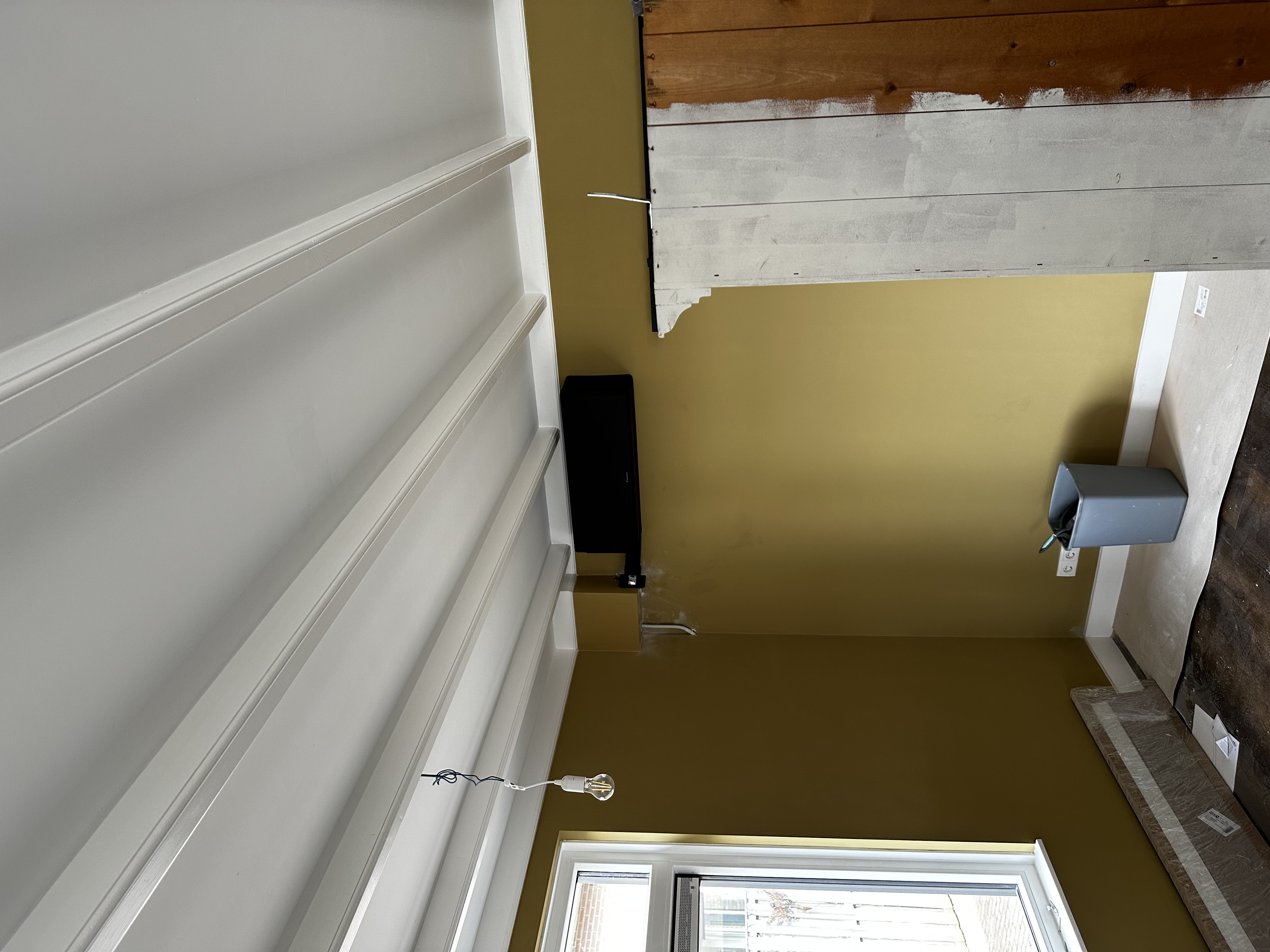 De afbeelding toont een net geïnstalleerde airconditioningseenheid aan de muur in een kamer met een eenvoudige afwerking.