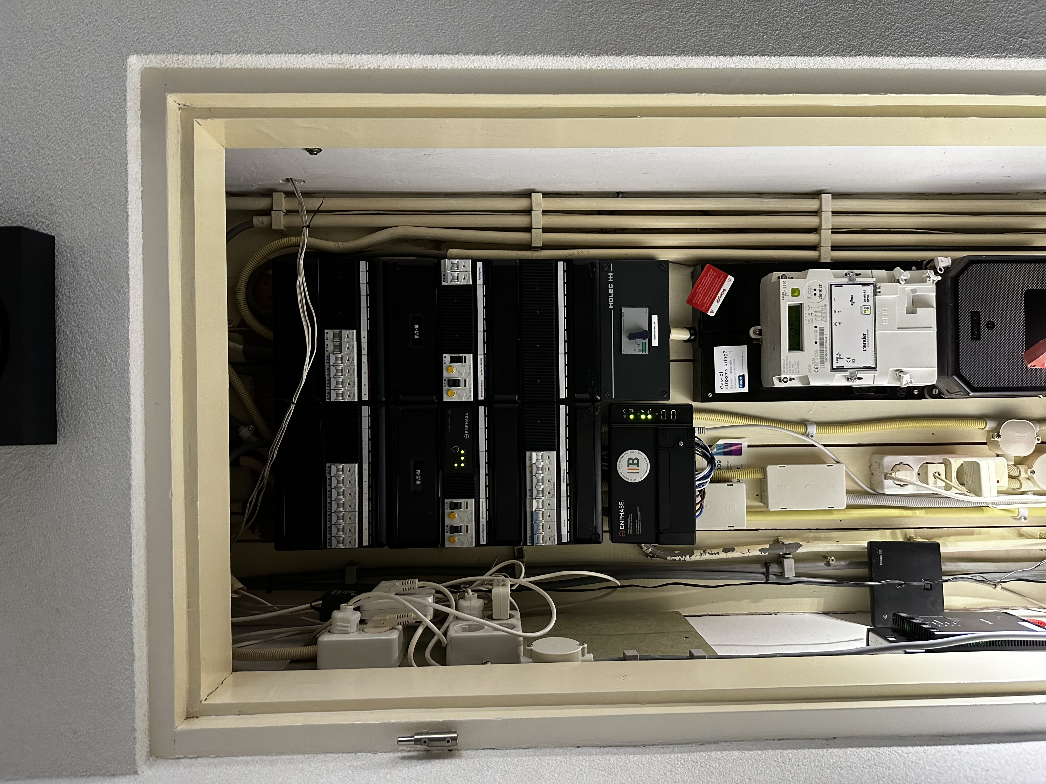 De afbeelding toont een meterkast met diverse schakelaars en apparatuur, waarschijnlijk gerelateerd aan een zonnepaneelsysteem.