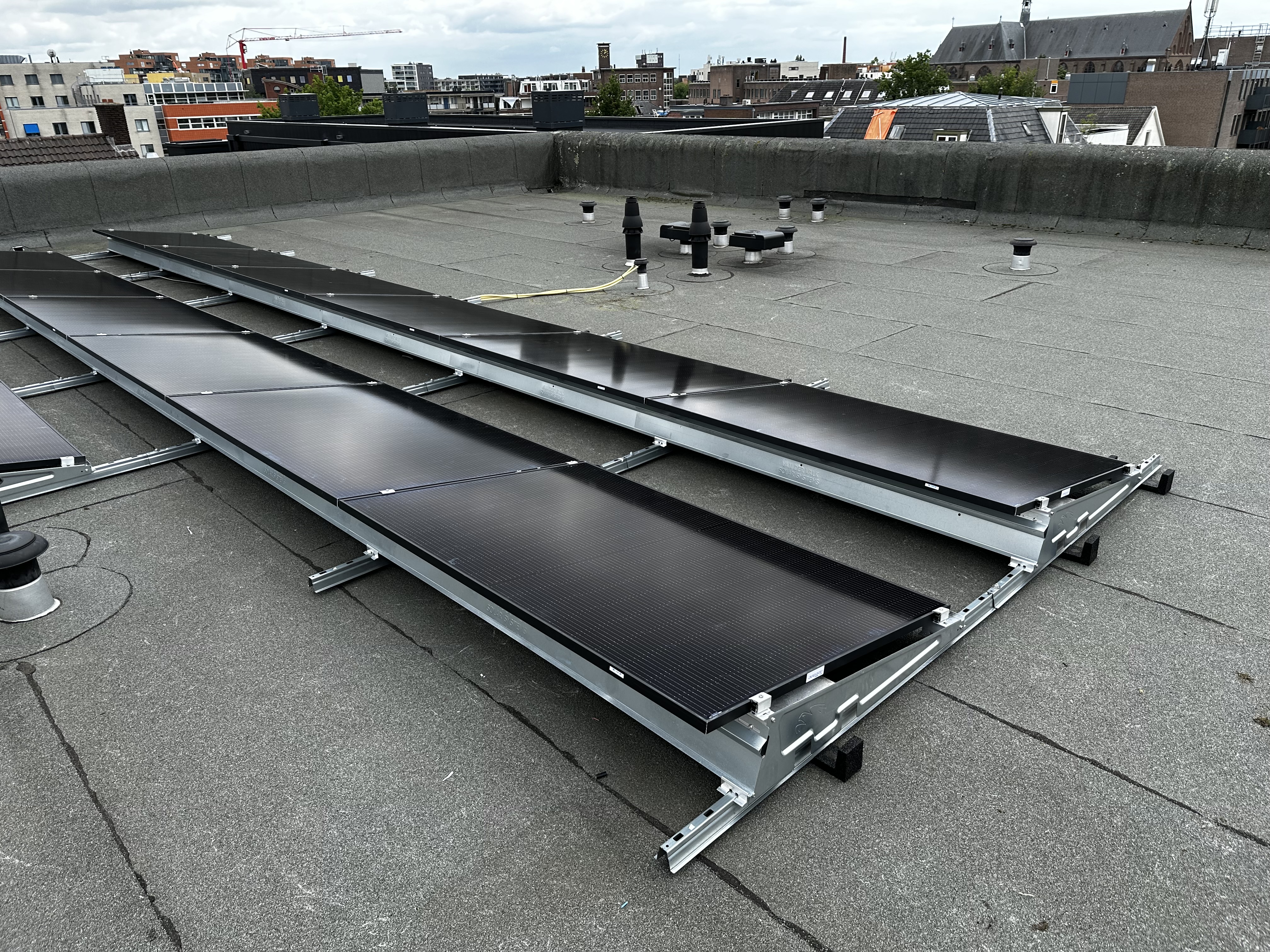 Deze foto toont een installatie van zonnepanelen op een plat dak, klaar voor aansluiting en gebruik.