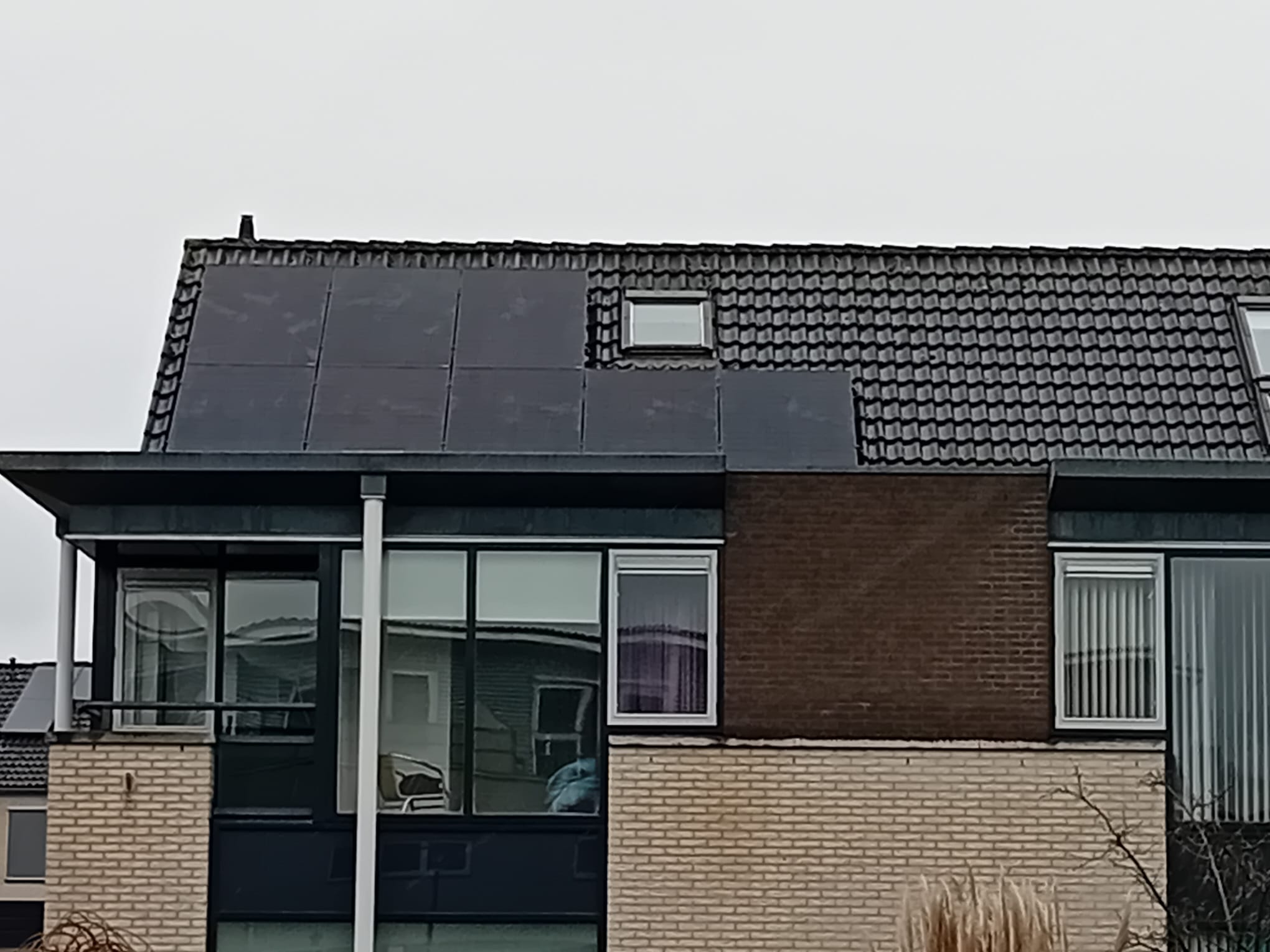 De foto toont een installatie van zonnepanelen op een hellend dak van een woning.